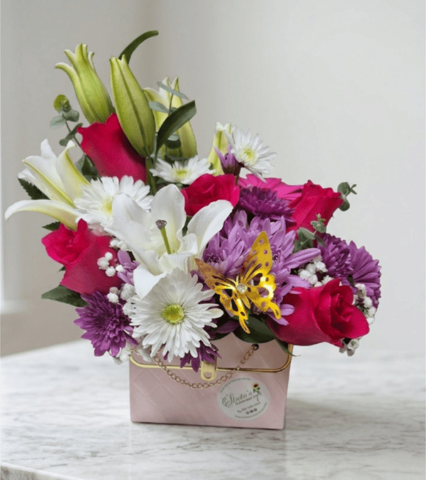 Bouquet of pink roses, white lilies, and purple daisies in a pink box