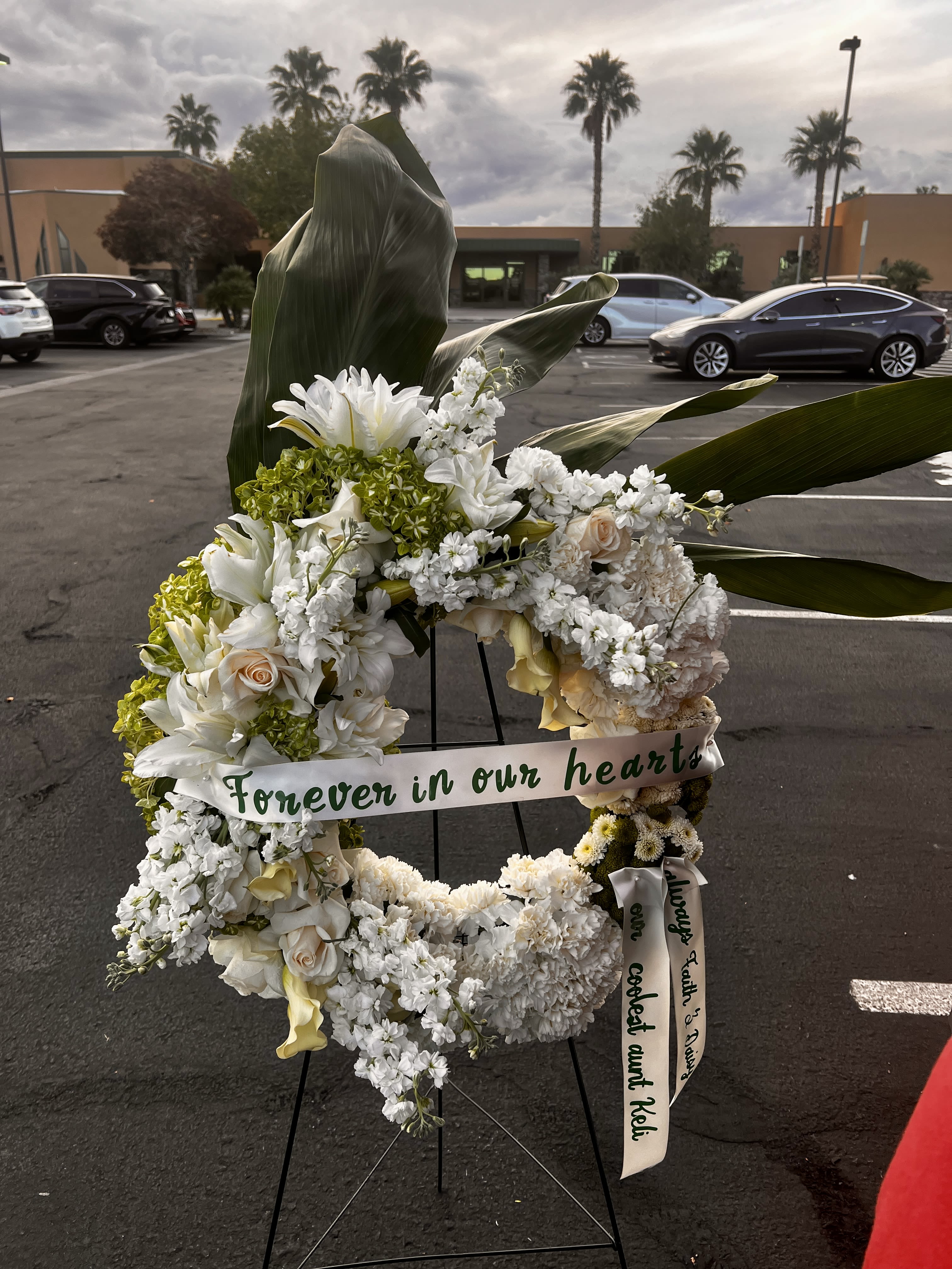 White floral wreath on an easel with a memorial ribbon