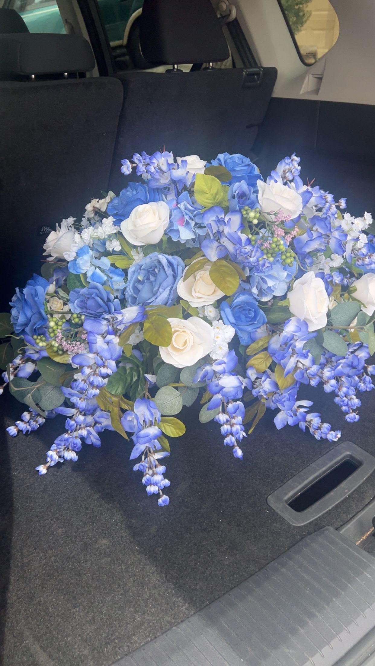 Blue and white rose bouquet with trailing blue flowers in a car trunk