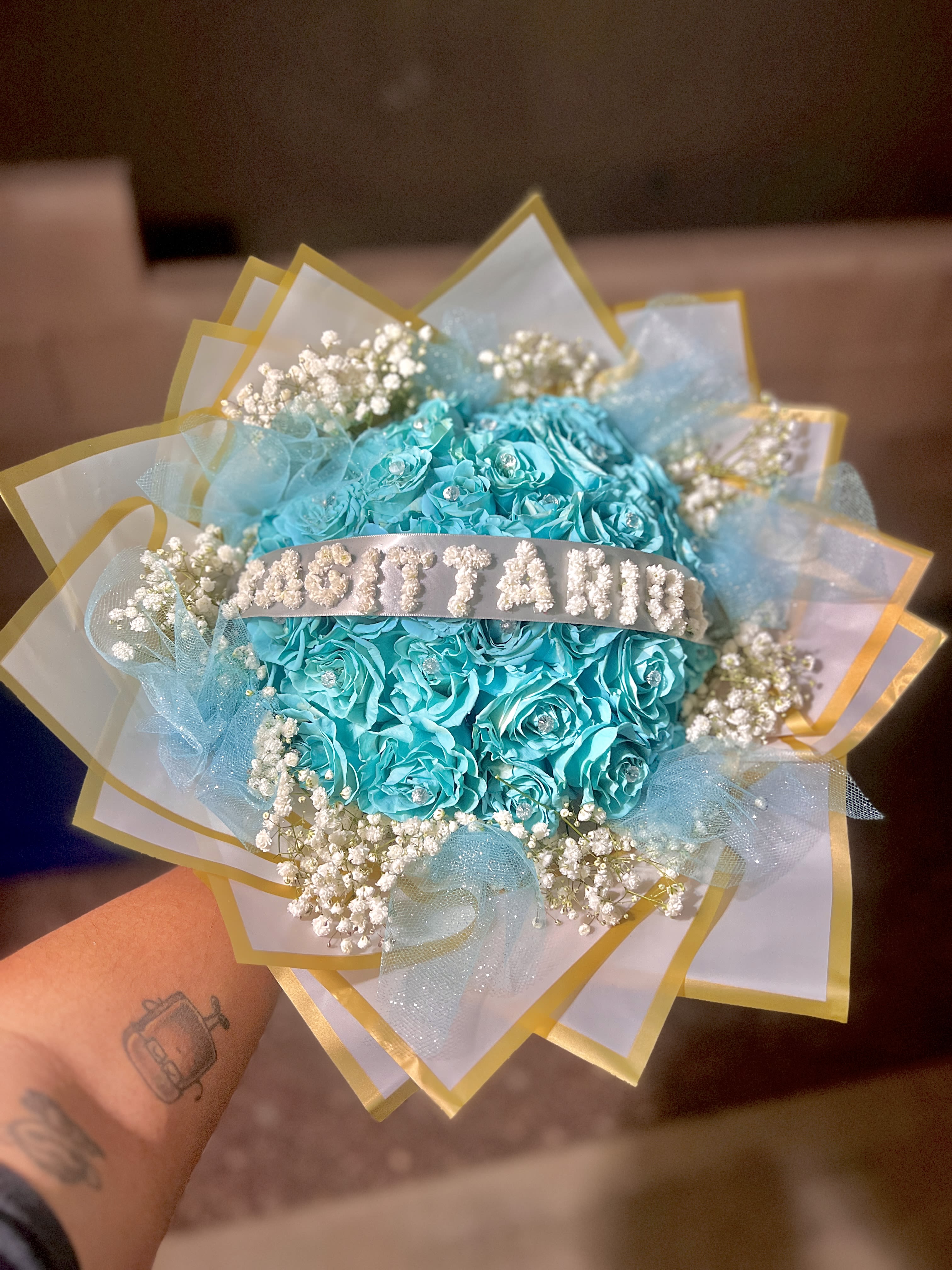 Turquoise rose bouquet with baby's breath and gold-edged wrapping