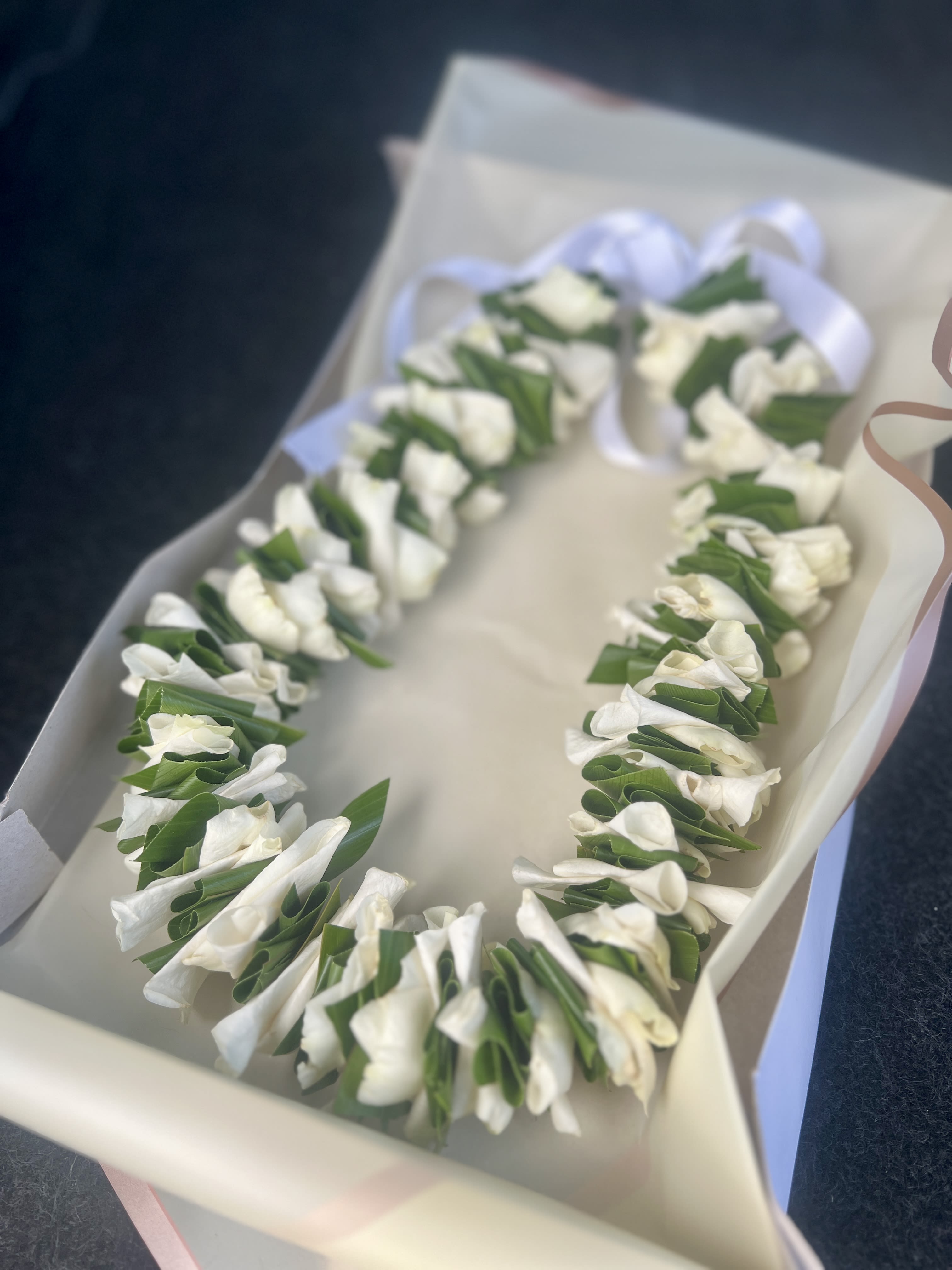 White floral lei in a gift box with a ribbon