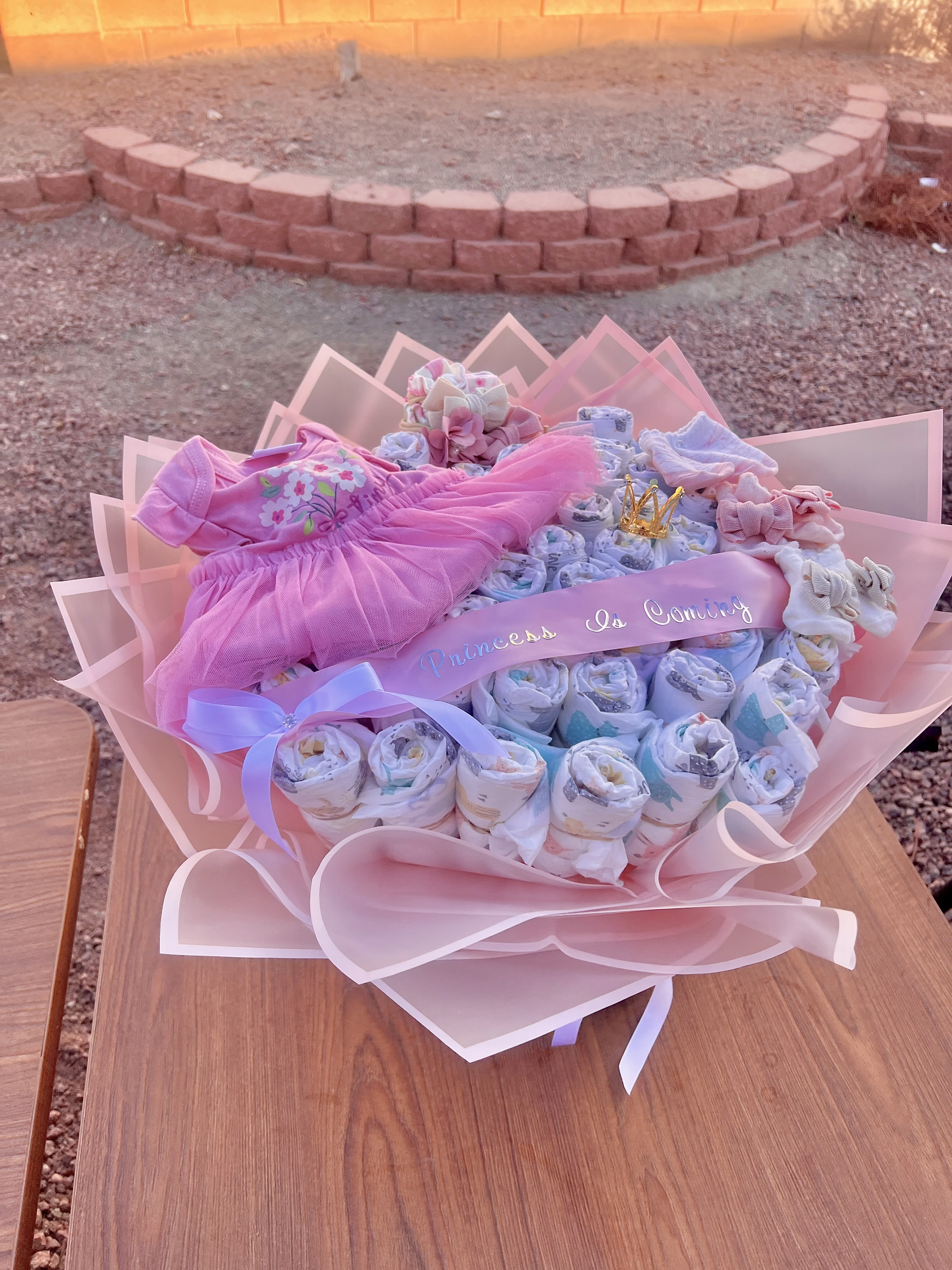 Pink baby gift bouquet with folded clothes and ribbons