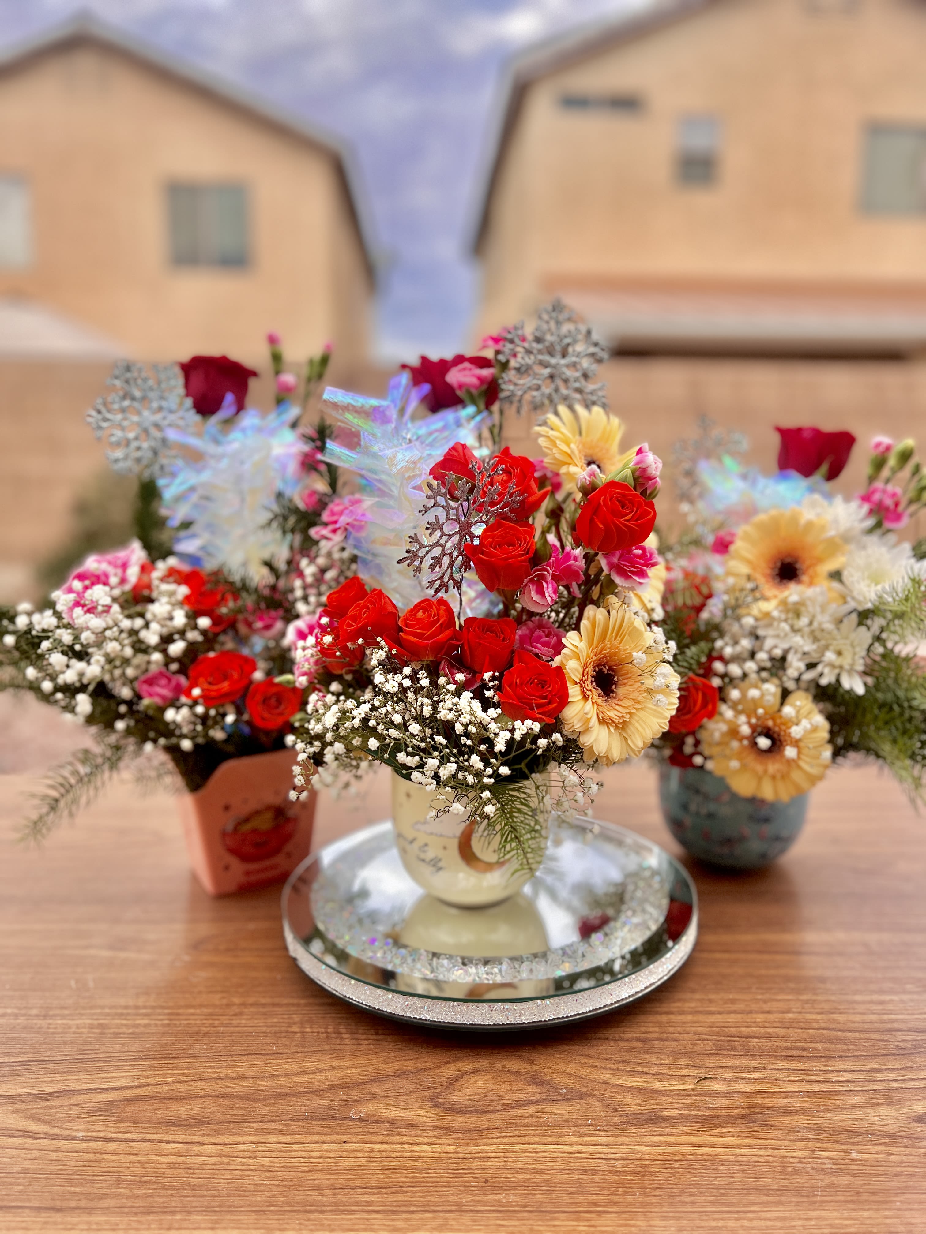 Three colorful flower arrangements in small vases on a table