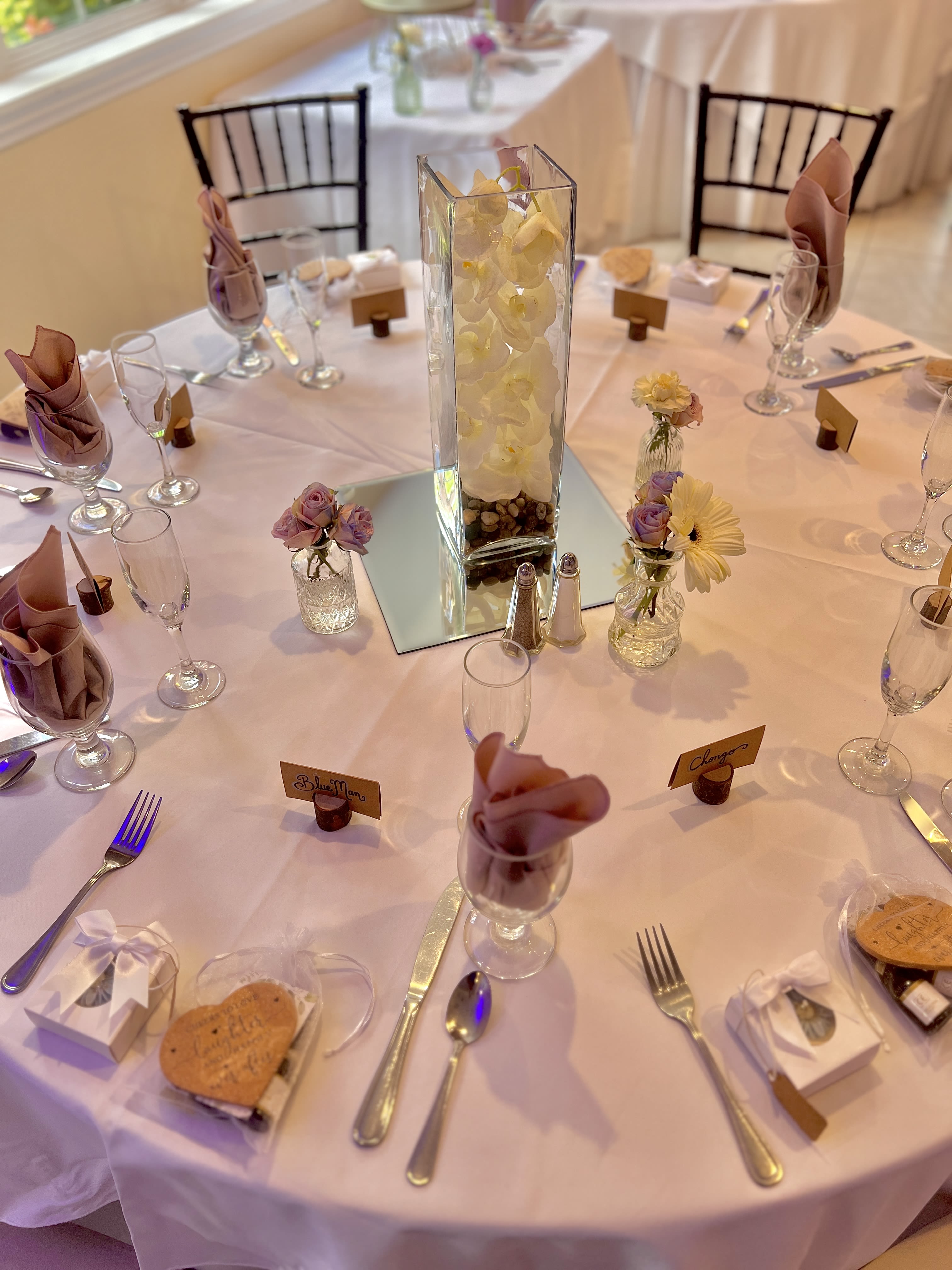 Round banquet table with small floral centerpieces and a tall orchid vase
