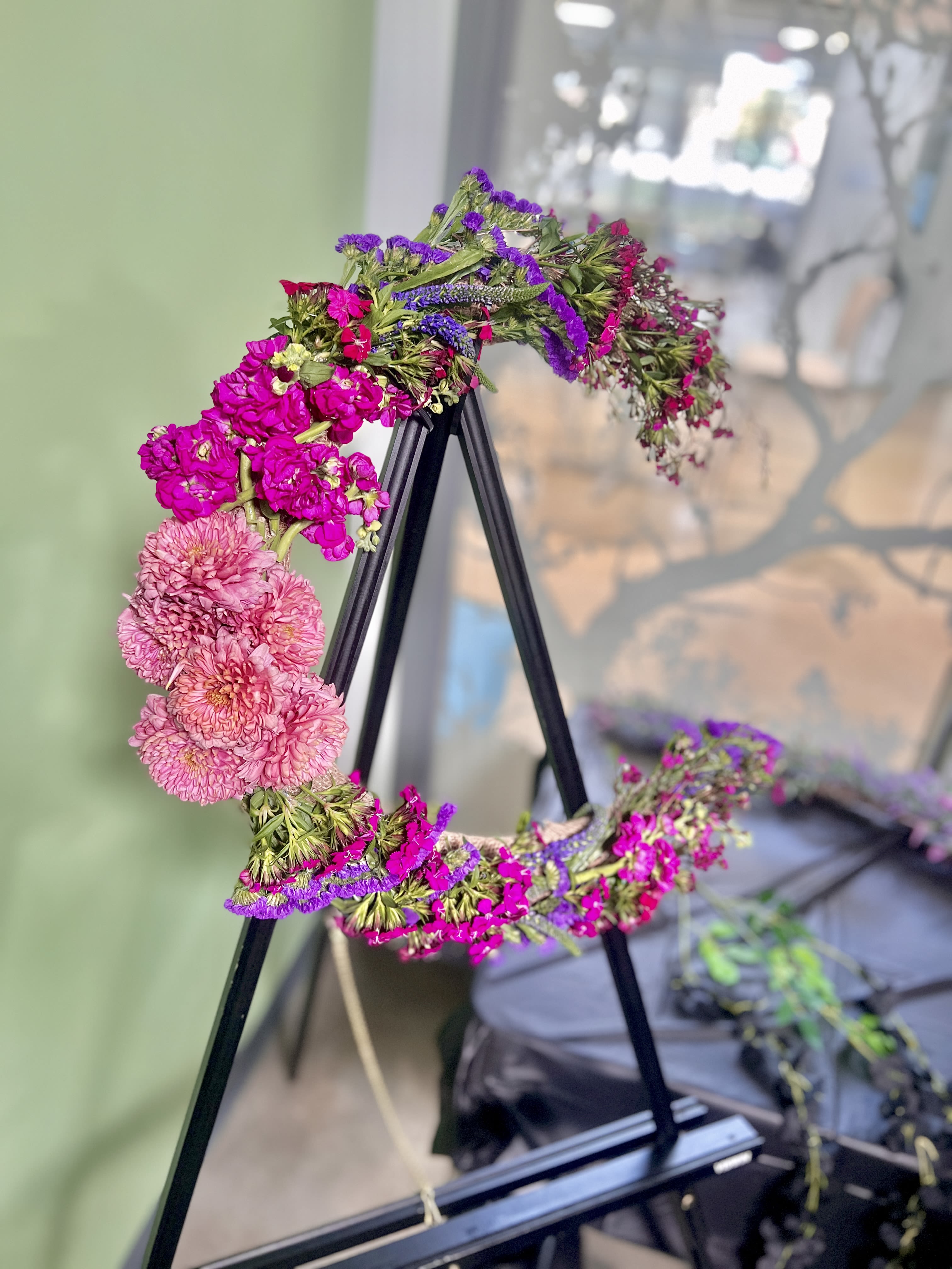 Floral wreath with pink and purple blooms on a black stand