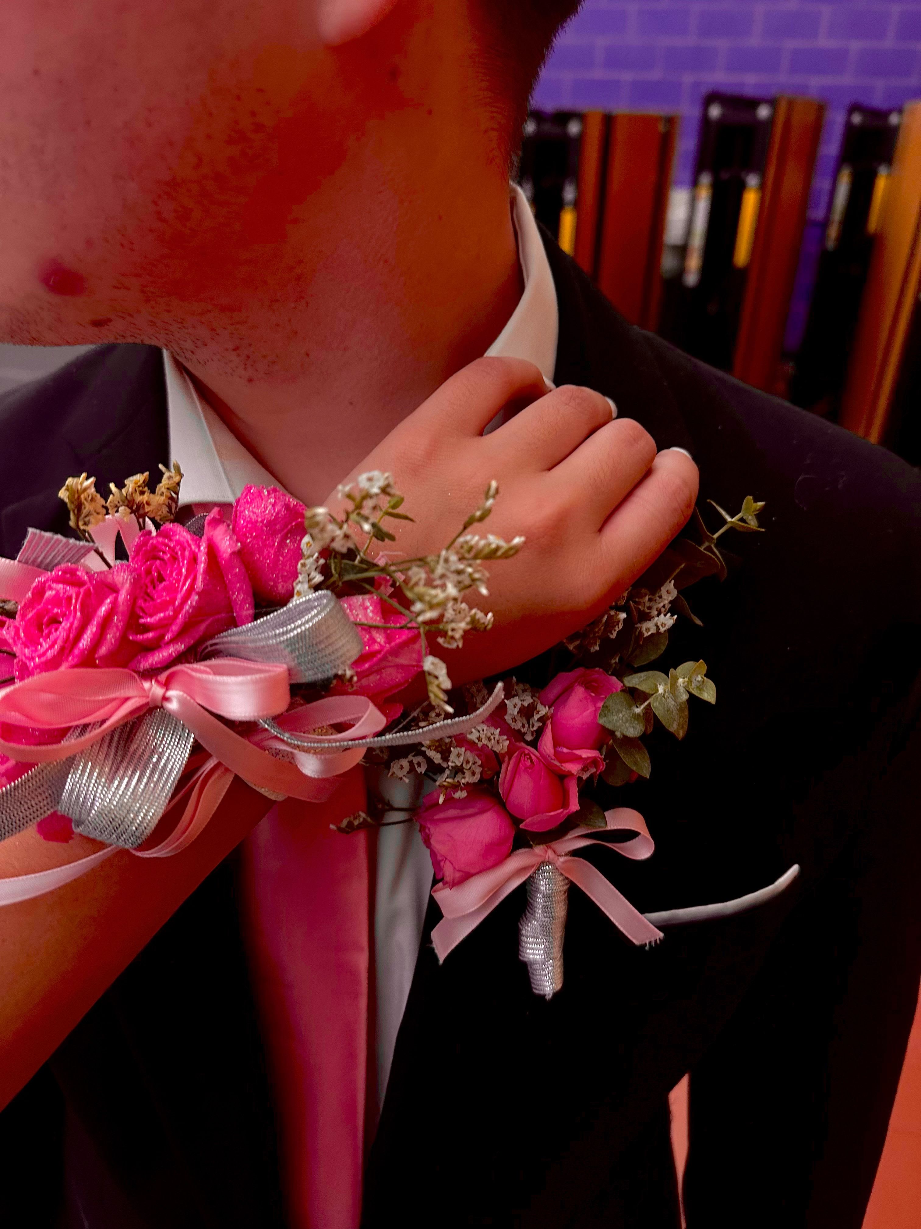 Pink rose corsage on a suit wrist with ribbon accents