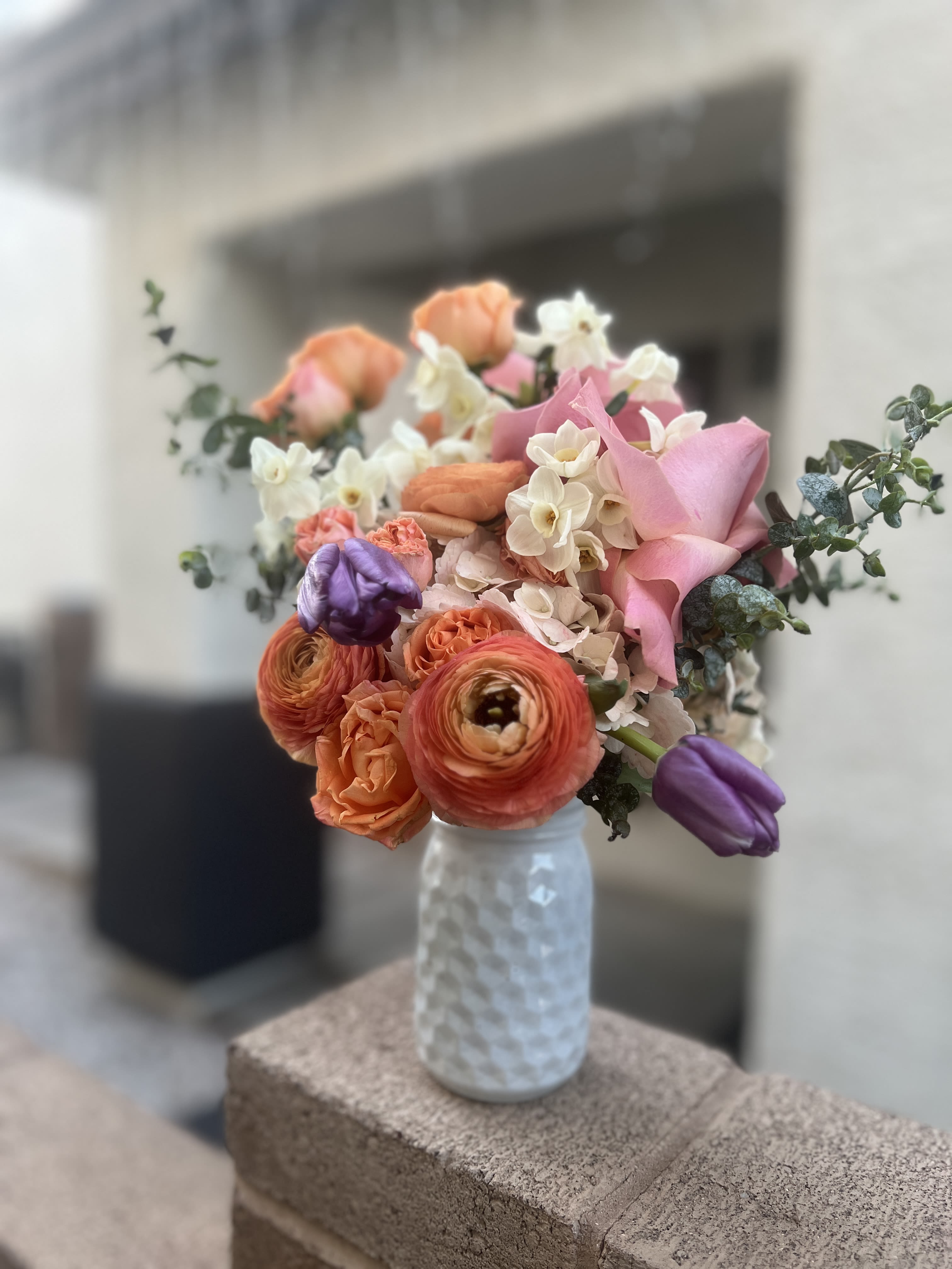 Bouquet of pink, orange, and white flowers in a textured glass vase