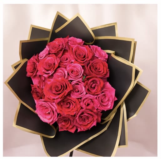 Bouquet of pink and red roses wrapped in black paper with gold trim