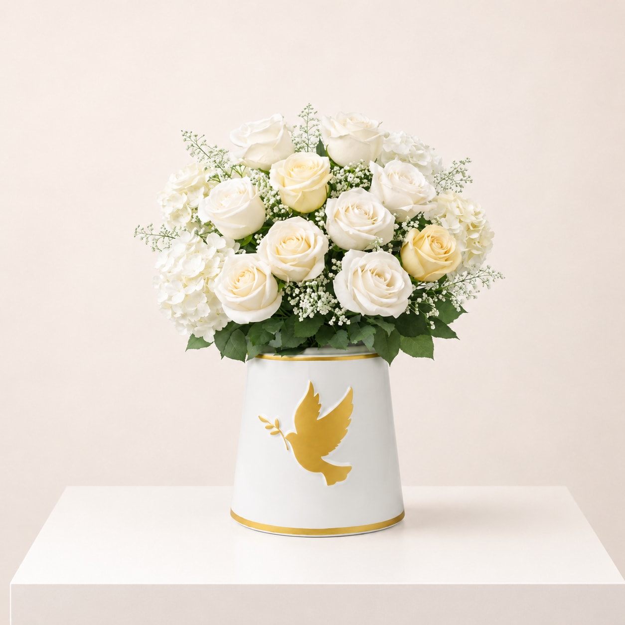 White roses and hydrangeas in a white vase with a gold dove design