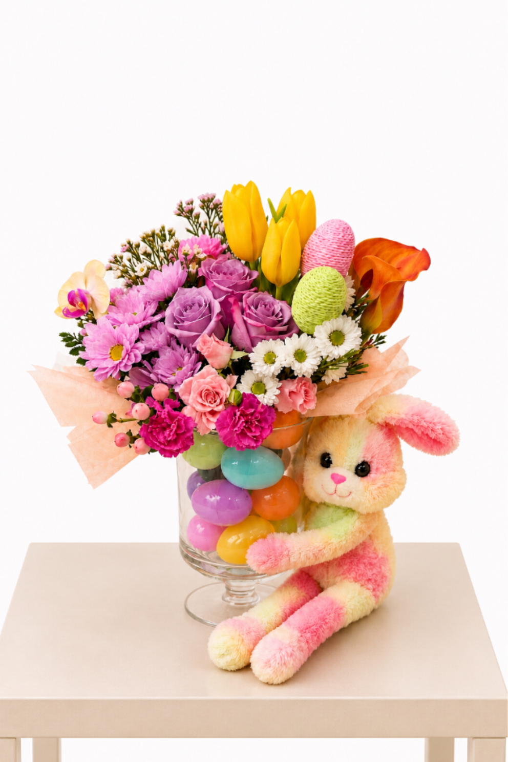 Garden Gift Delight | Designer Choice - Celebrate with this vibrant  flower arrangement, beautifully designed in a clear glass vase filled with colorful decorative accents and accompanied by an adorable plush bunny. A joyful blend of fresh spring florals and playful charm, perfect for brightening any space.  Perfect for: spring celebrations, birthdays, baby showers, Easter gifts, or sending a bright and joyful surprise for any occasion.  Available for local flower delivery throughout Naples, Bonita Springs, Estero, Fort Myers and Fort Myers Beach.  Designer’s Choice: Each arrangement is uniquely designed using the freshest seasonal flowers available. Flower varieties, colors and containers may vary while maintaining the overall style, value and beauty of the design.