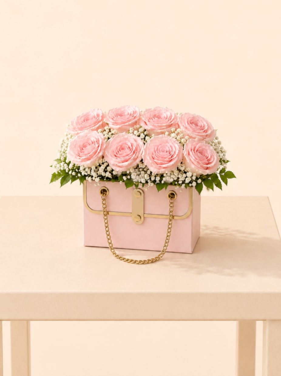 Blush Pink Purse  - Soft blush roses styled in a full, rounded design with fresh greenery and delicate berry accents, beautifully arranged in our signature pink purse-style box with elegant gold details. Sweet, feminine, and effortlessly refined, this design is perfectly photo-ready from every angle.  Perfect for Valentine’s Day, birthdays, Mother’s Day, anniversaries, thank you gestures, welcoming a new baby, thinking of you, congratulations, or a sweet and elegant “just because” surprise.  Available for local flower delivery throughout Naples, Bonita Springs, Estero, Fort Myers and Fort Myers Beach.  Designer’s Choice: Each arrangement is uniquely designed using the freshest seasonal flowers available. Flower varieties, colors and containers may vary while maintaining the overall style, value and beauty of the design.