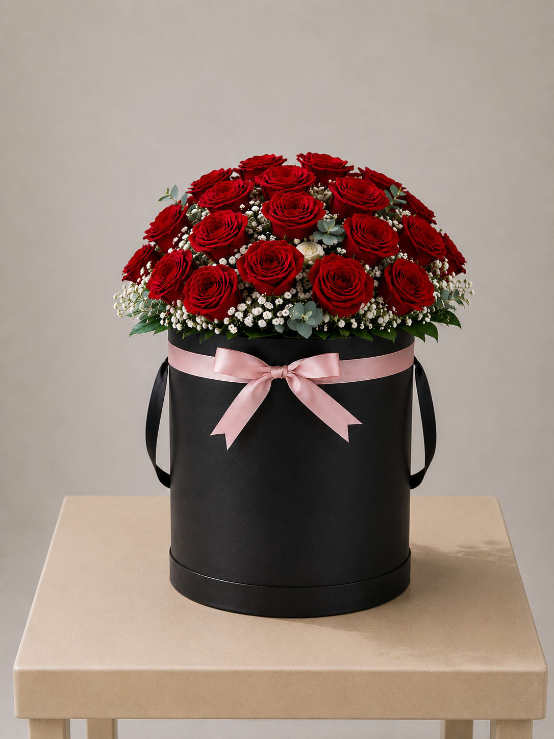 Classic Red Rose Hatbox – Tall - This elegant arrangement features 24 red roses, designed in a tall black hatbox and finished with delicate white accents and a soft blush ribbon. A timeless floral gift, perfect for celebrating love and meaningful moments.  Perfect For: Mother’s Day, Women’s Day, Anniversary, Birthday, Just Because  Available for local flower delivery throughout Naples, Bonita Springs, Estero, Fort Myers and Fort Myers Beach.  Designer’s Choice: Each arrangement is uniquely designed using the freshest seasonal flowers available. Flower varieties, colors and containers may vary while maintaining the overall style, value and beauty of the design.