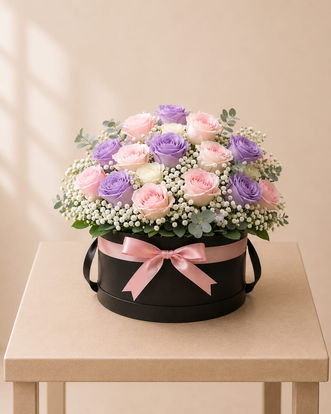 Pastel Rose Hatbox - This graceful floral design features 18 roses in blush, lavender, and ivory hues, beautifully arranged with white accents and fresh greenery in a short black hatbox. Soft, timeless, and thoughtfully crafted.  Perfect For: Mother’s Day, Women’s Day, Birthday, Get Well, Just Because.  Available for local flower delivery throughout Naples, Bonita Springs, Estero, Fort Myers and Fort Myers Beach.  Designer’s Choice: Each arrangement is uniquely designed using the freshest seasonal flowers available. Flower varieties, colors and containers may vary while maintaining the overall style, value and beauty of the design.