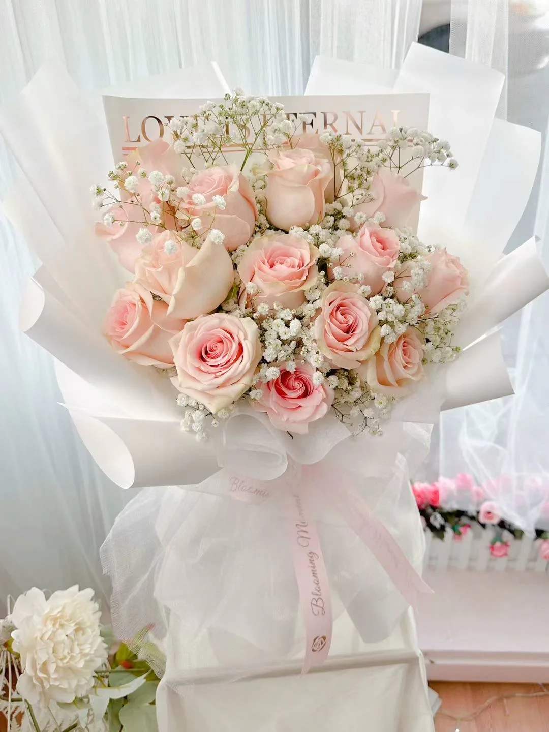 [FRESH FLOWER] Blushing Serenity Pink Rose Bouquet - 12 stems pink rose with gyp and white wrapping style.  Experience the timeless elegance of the Blushing Serenity Bouquet, a delicate arrangement that captures the essence of grace and beauty. This exquisite bouquet features twelve lush pink roses, each symbolizing admiration and sweetness, perfectly paired with ethereal baby's breath that adds a touch of airy charm. Enveloped in pristine white wrapping, the bouquet exudes purity and sophistication, making it an ideal gift for any special occasion. Whether celebrating a milestone, expressing heartfelt emotions, or simply brightening someone's day, the Blushing Serenity Bouquet is a captivating choice that speaks volumes with its subtle yet profound beauty.  *Our imported 60-70cm long stem roses from Ecuador are carefully cut to the appropriate length to achieve the desired appearance. 