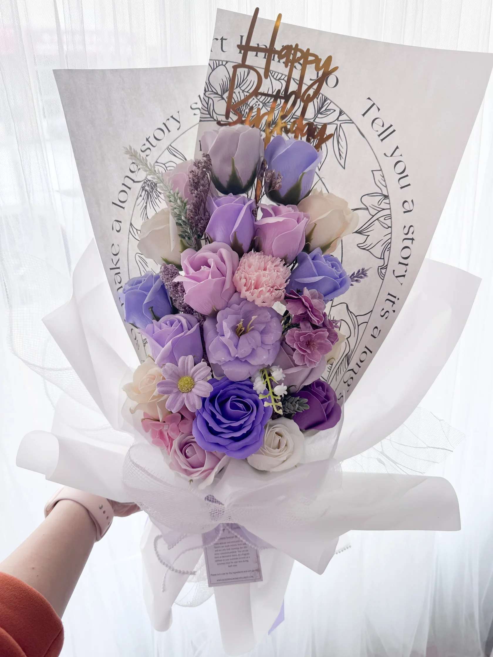 Bouquet of purple and pink roses wrapped in white paper