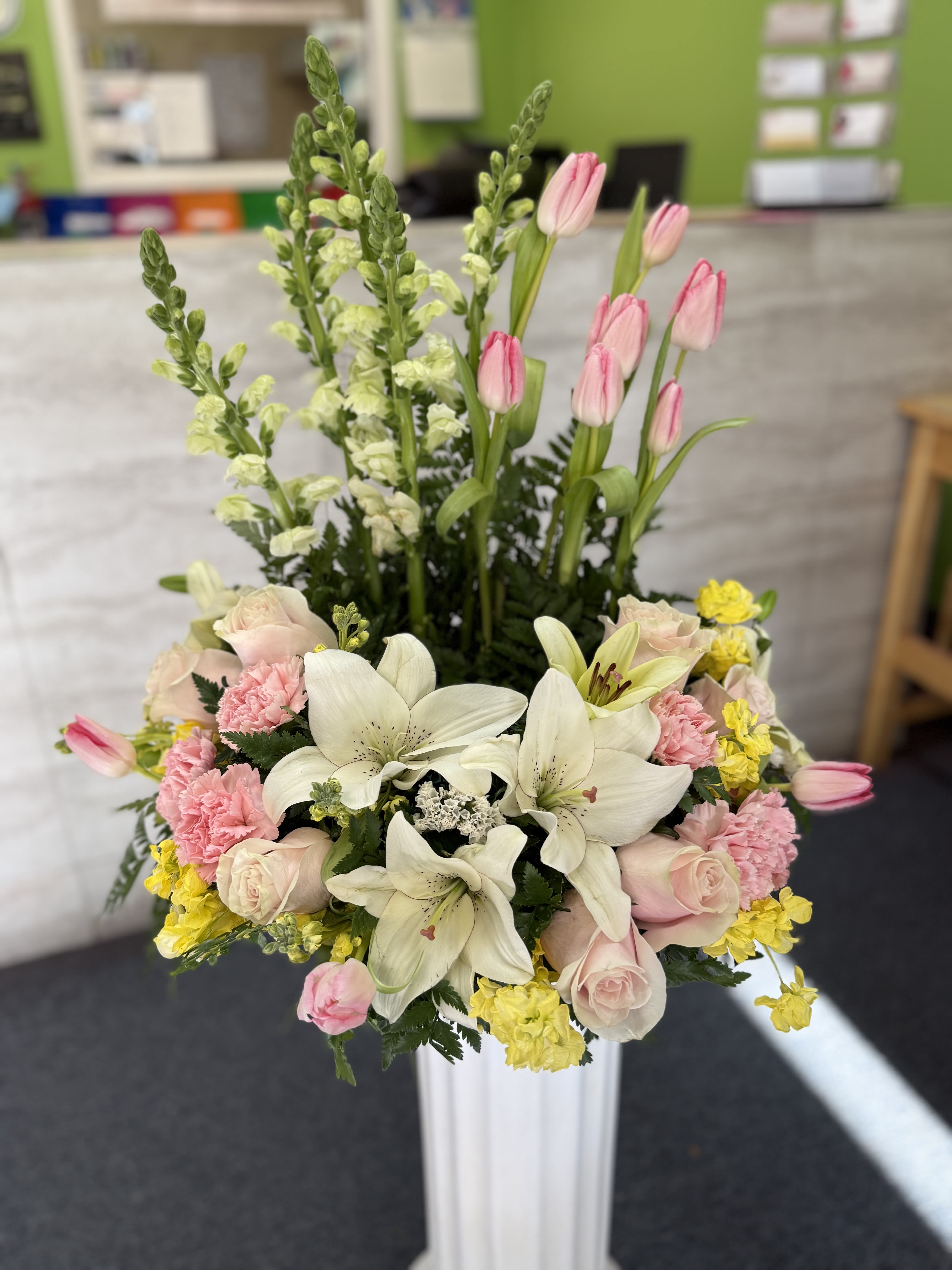 Pink tulips, white lilies, and roses in a tall white vase