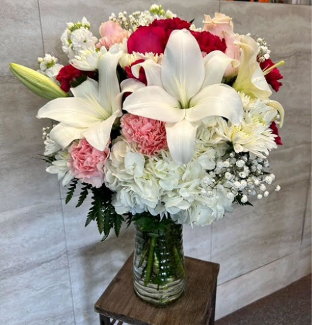 Bouquet of white lilies, red and pink flowers in a glass vase