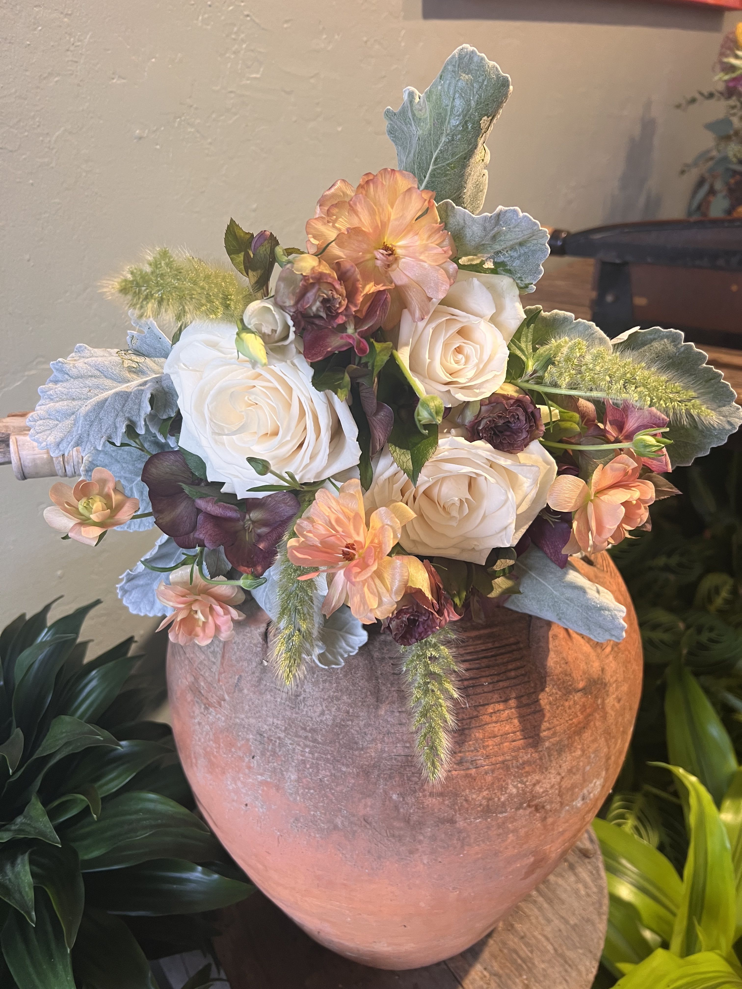 Blush and Clay  - Soft vanilla roses, peachy petals, and cozy silver foliage all snuggled together in the cutest luxury combo. Inspired by pastel dreams and café windows, this bouquet is elegant, deliciously pretty, and guaranteed to make hearts melt.