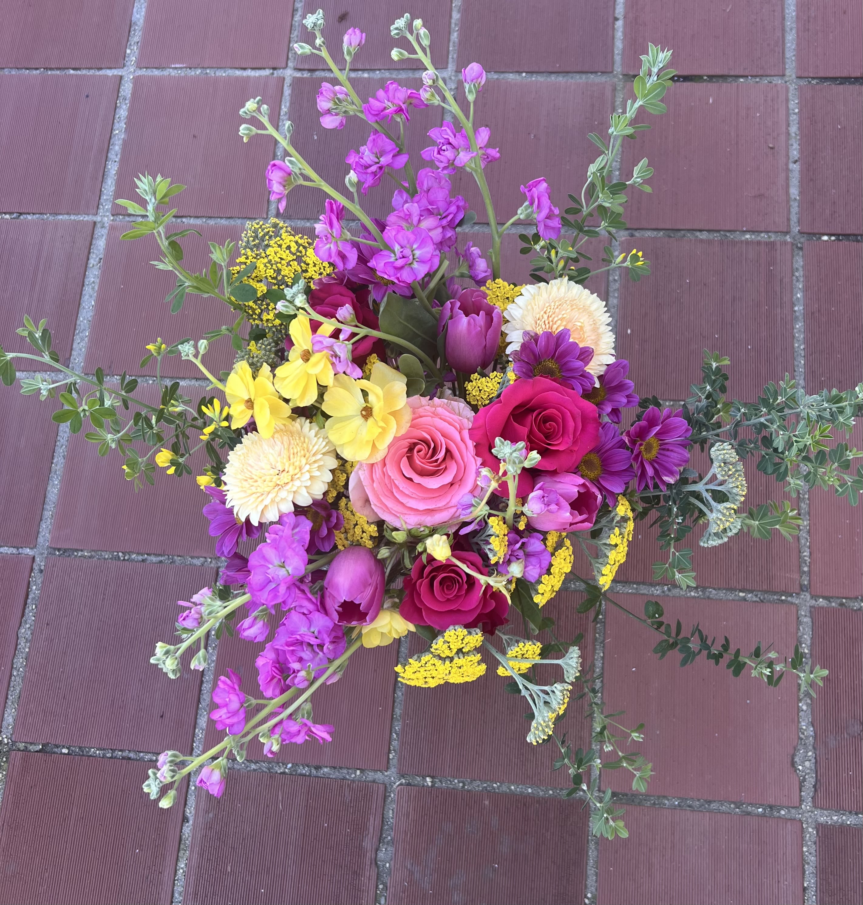 Vivid Garden  - Fresh, bold, and full of life, Vivid Garden is a vibrant floral design inspired by the natural beauty of a blooming spring garden. Featuring hot pink and blush roses, rich magenta stock, purple tulips, sunny yellow accents, and textured seasonal greenery, this arrangement is thoughtfully styled for movement and depth. The dynamic mix of fuchsia, lavender, soft pink, and golden tones creates a bright yet refined presence that feels both joyful and sophisticated. Designed in a clear glass vase, Vivid Garden brings color, texture, and modern elegance into any space. Perfect for birthdays, celebrations, congratulations, or sending an uplifting surprise “just because.” Handcrafted and hand-delivered by Floral Girl Flowers in Vallejo and throughout the Bay Area, including San Francisco.