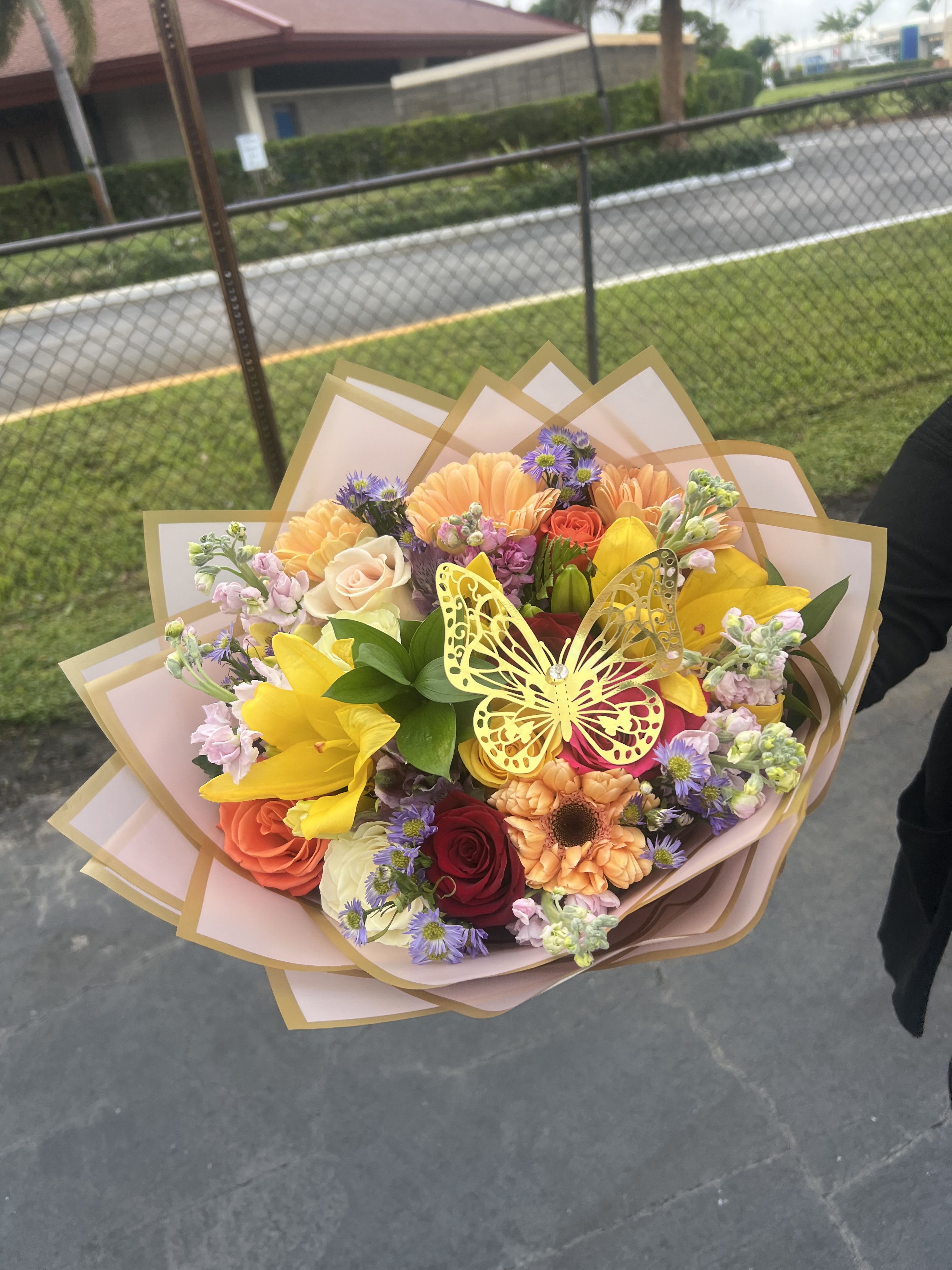 Colorful mixed bouquet with roses, lilies, and a butterfly decoration