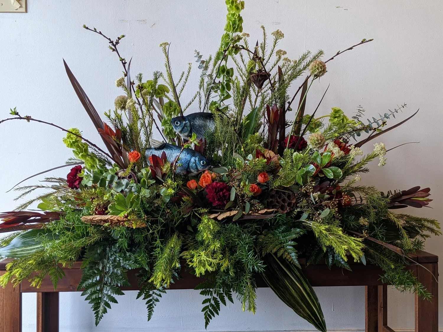 Large floral arrangement with fish decorations and mixed greenery