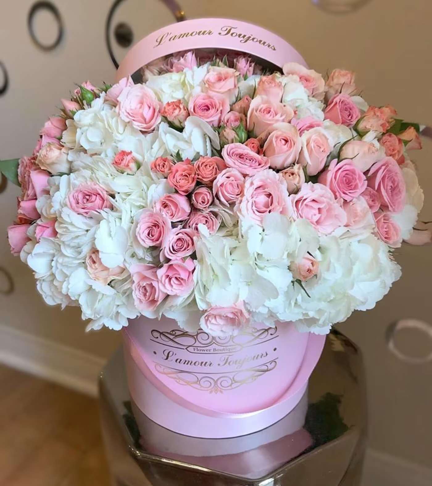 Pink and white roses arranged in a round hatbox