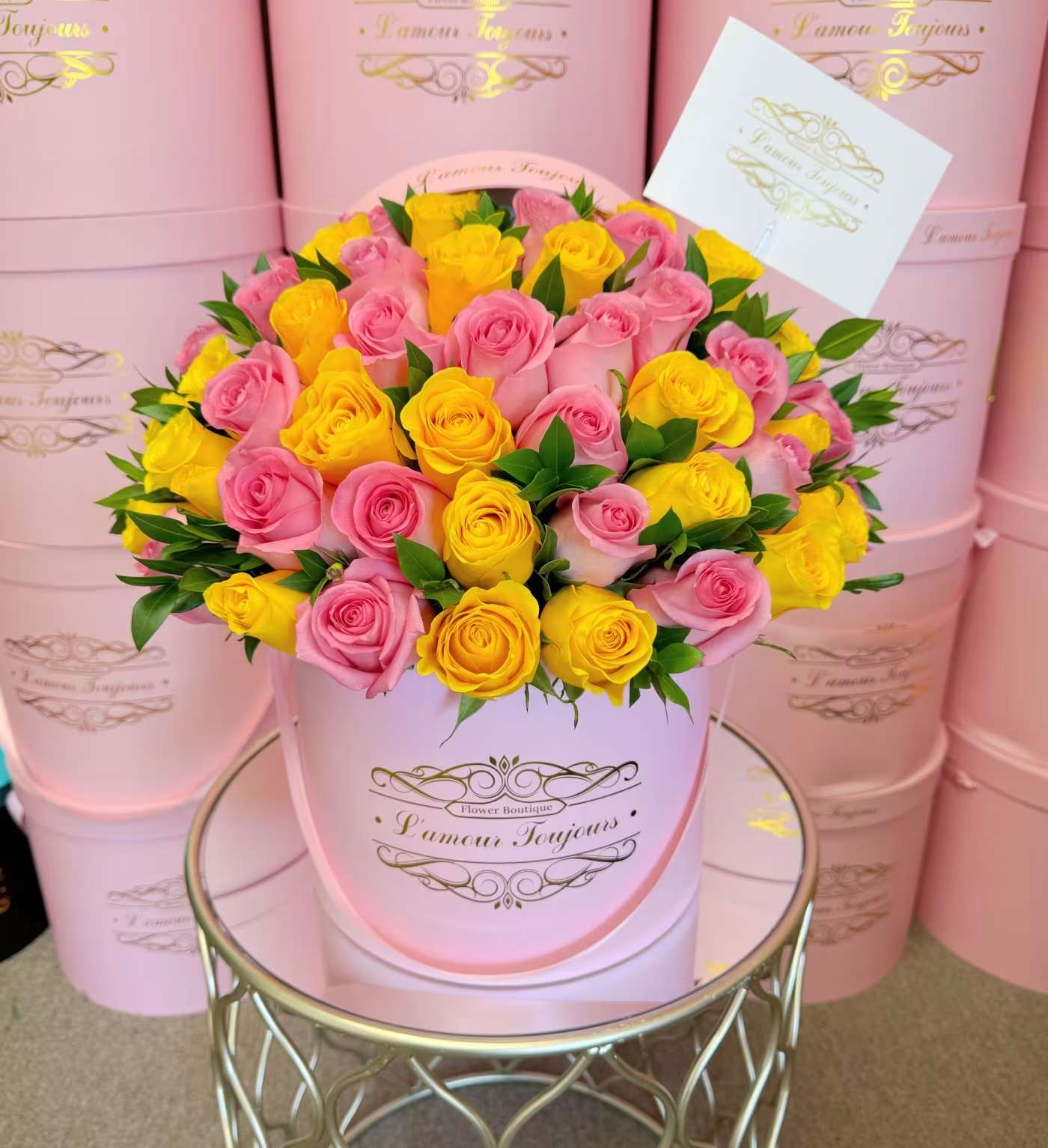 Pink and yellow roses arranged in a round pink hat box