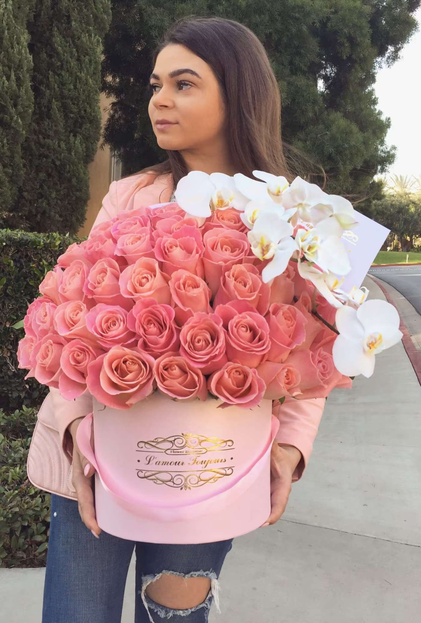 Woman holding a large pink rose box with white orchids
