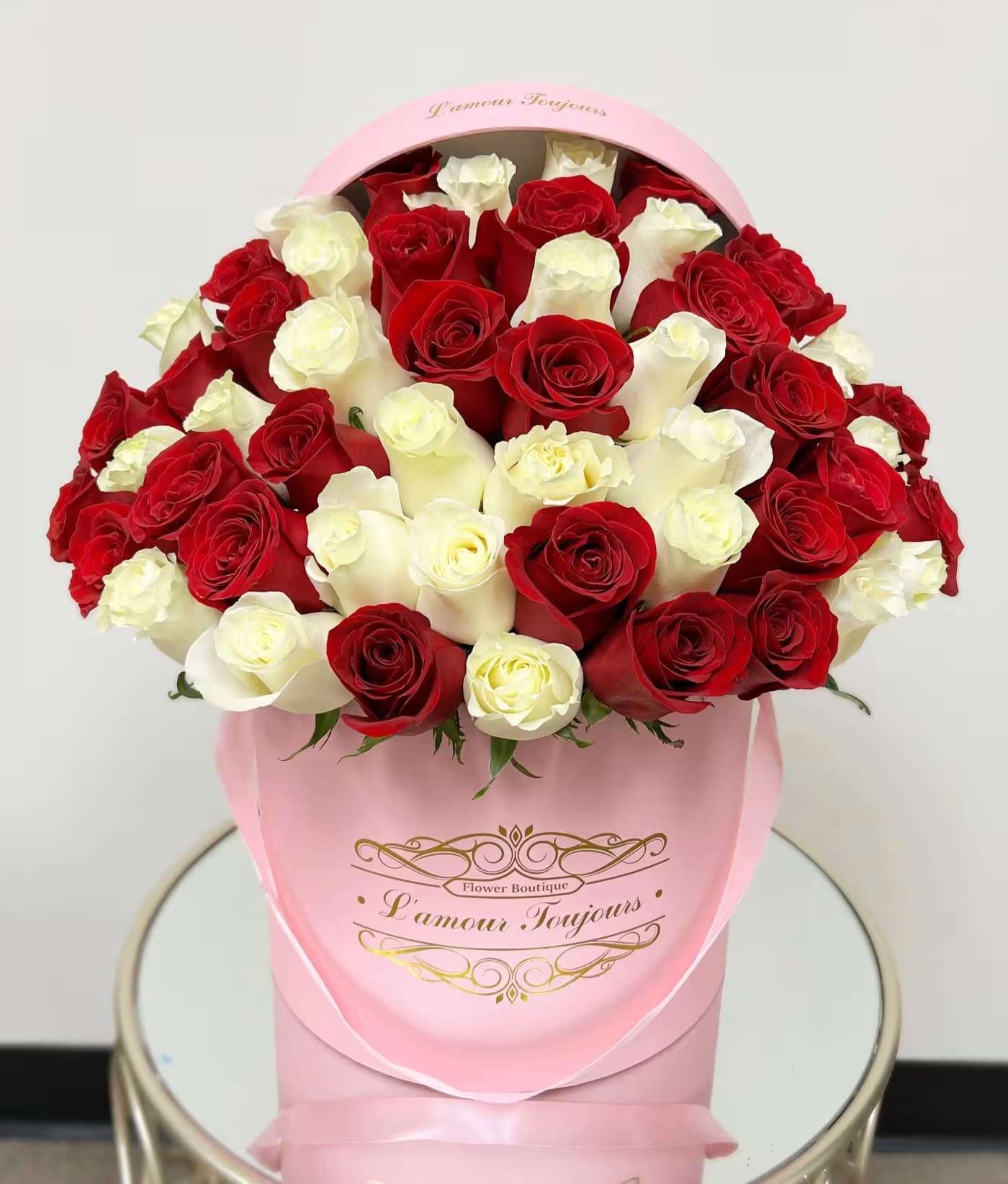 Bouquet of red and white roses in a pink hat box