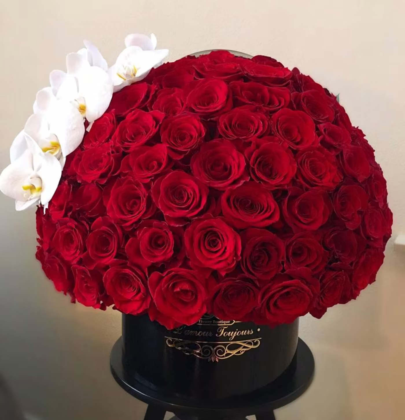 Large dome of red roses with white orchids in a black hat box