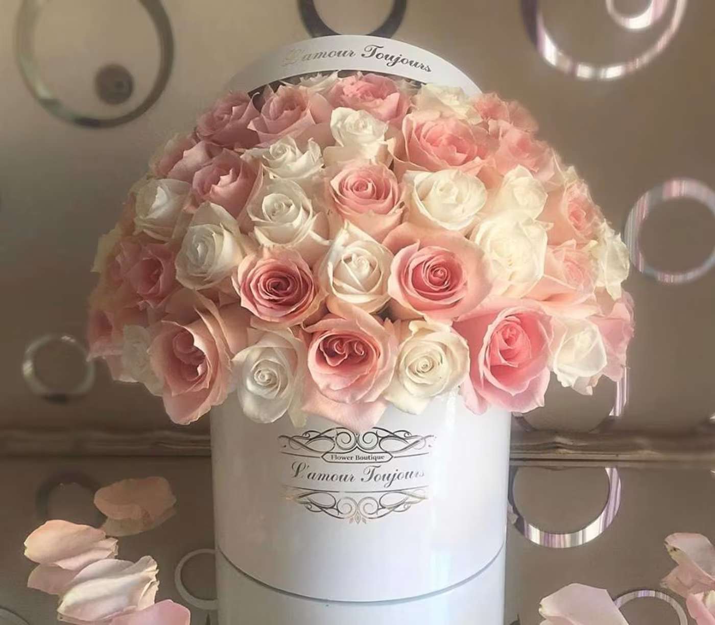 Pink and white roses arranged in a white hat box