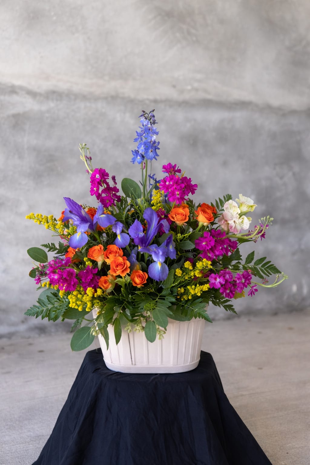 Wildflower Jubilee - A vibrant celebration of color and joy, Wildflower Jubilee brings together a lively mix of blooms in rich blues, purples, pinks, and warm sunset tones. Designed with a garden-inspired feel, this arrangement features a playful blend of seasonal flowers, soft textures, and fresh greenery—perfect for birthdays, celebrations, or simply brightening someone’s day.  > Colors and exact flowers may vary slightly based on seasonal availability > Designed fresh daily with the best blooms in shop > Each arrangement is one-of-a-kind while maintaining the overall style