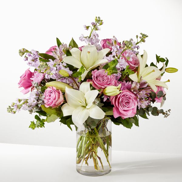 Daydreamer Bouquet - Daydreamer Bouquet is a timeless arrangement featuring elegant white lilies paired with soft lavender roses and lush greenery. This refined design offers a graceful blend of purity and gentle color, perfect for heartfelt moments, sympathy expressions, or adding a touch of serene beauty to any setting.