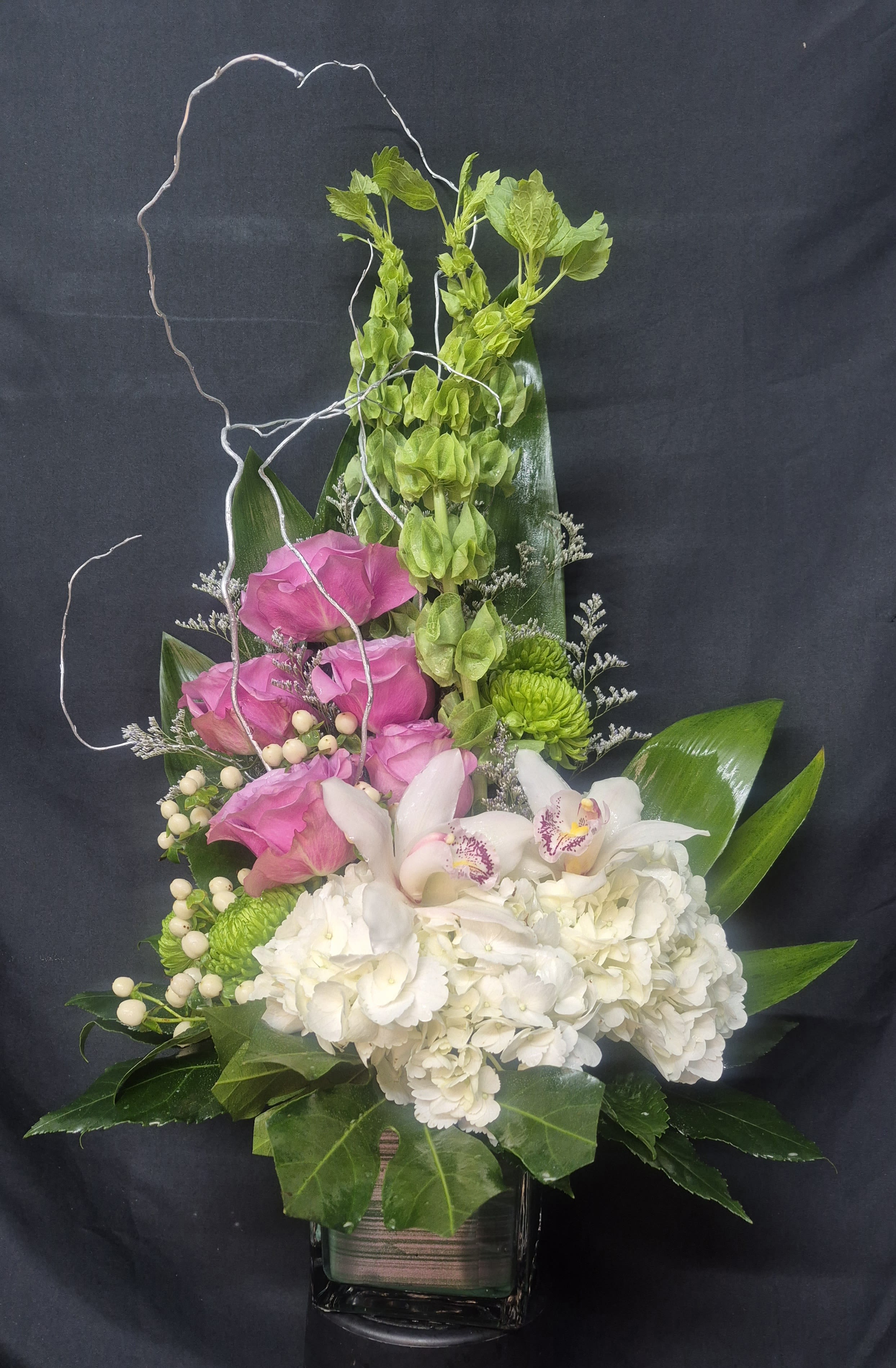 Tall floral arrangement with pink and white blooms in a glass vase