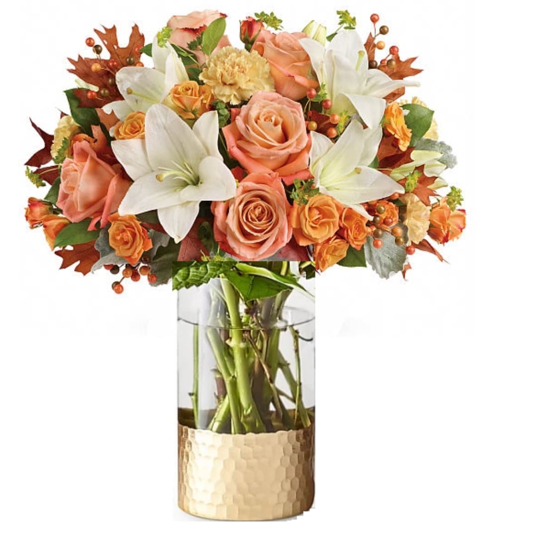 Peach roses and white lilies in a glass vase with a gold wrap