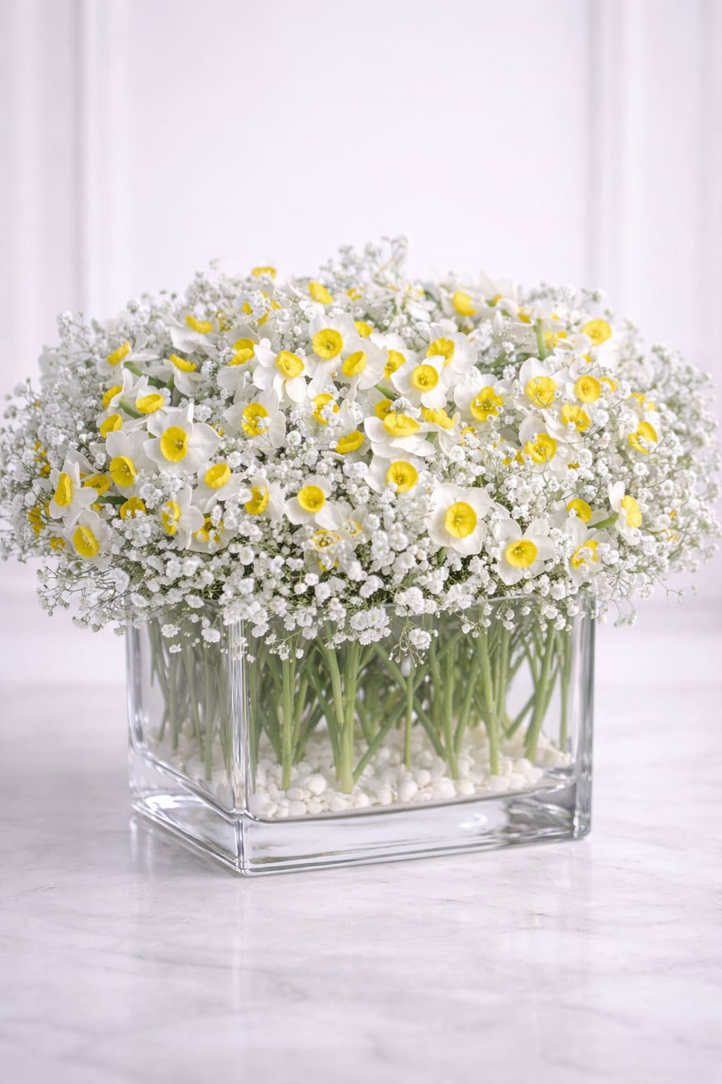 Sweet Spring Cube - Sweet Spring Cube by Oh Flower by Naz is a modern floral arrangement designed in a clear glass cube using a refined stone-based technique for a clean, minimal, and architectural look. Featuring fresh seasonal blooms arranged upright and evenly, this design highlights the natural beauty and structure of each flower while creating a light, elegant presentation.  Instead of traditional floral foam, smooth white stones are used to support the stems, allowing the flowers to stand beautifully straight while keeping the glass completely clear and visible from every angle. This intentional design choice creates a contemporary, high-end aesthetic perfect for modern homes and thoughtful gifting.  This arrangement is best enjoyed as a fresh, short-term design and is ideal for spring celebrations, birthdays, thank-you gifts, or simply brightening any space with effortless elegance.  Care Note: Please check the water daily to ensure the stones remain lightly hydrated.  Available for local flower delivery in Carlsbad, San Marcos, Vista, Oceanside, Encinitas, Del Mar, and Rancho Santa Fe, and surrounding North County San Diego areas.  Designed with care by Oh Flower by Naz.