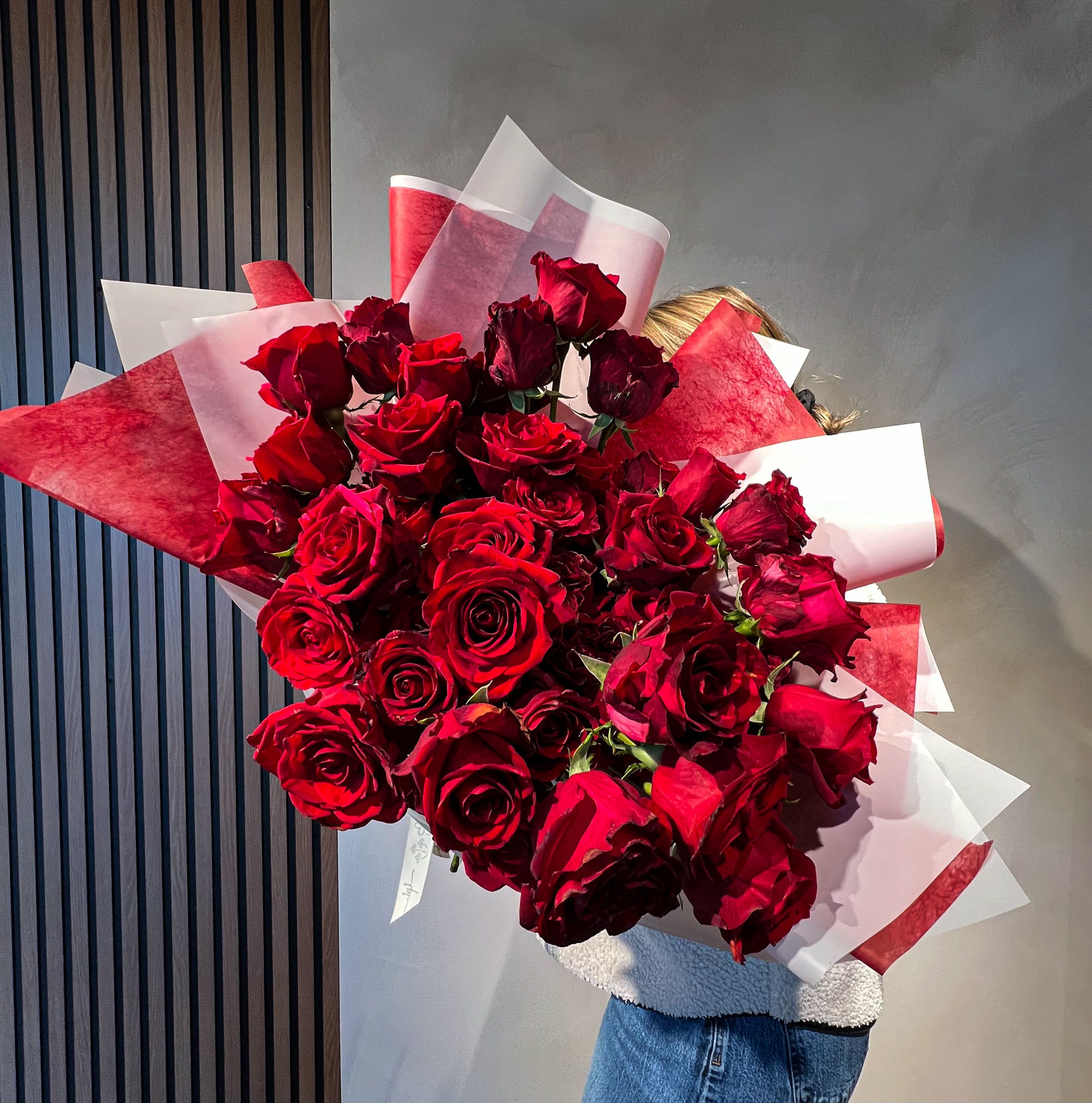 Large bouquet of red roses wrapped in red and white paper