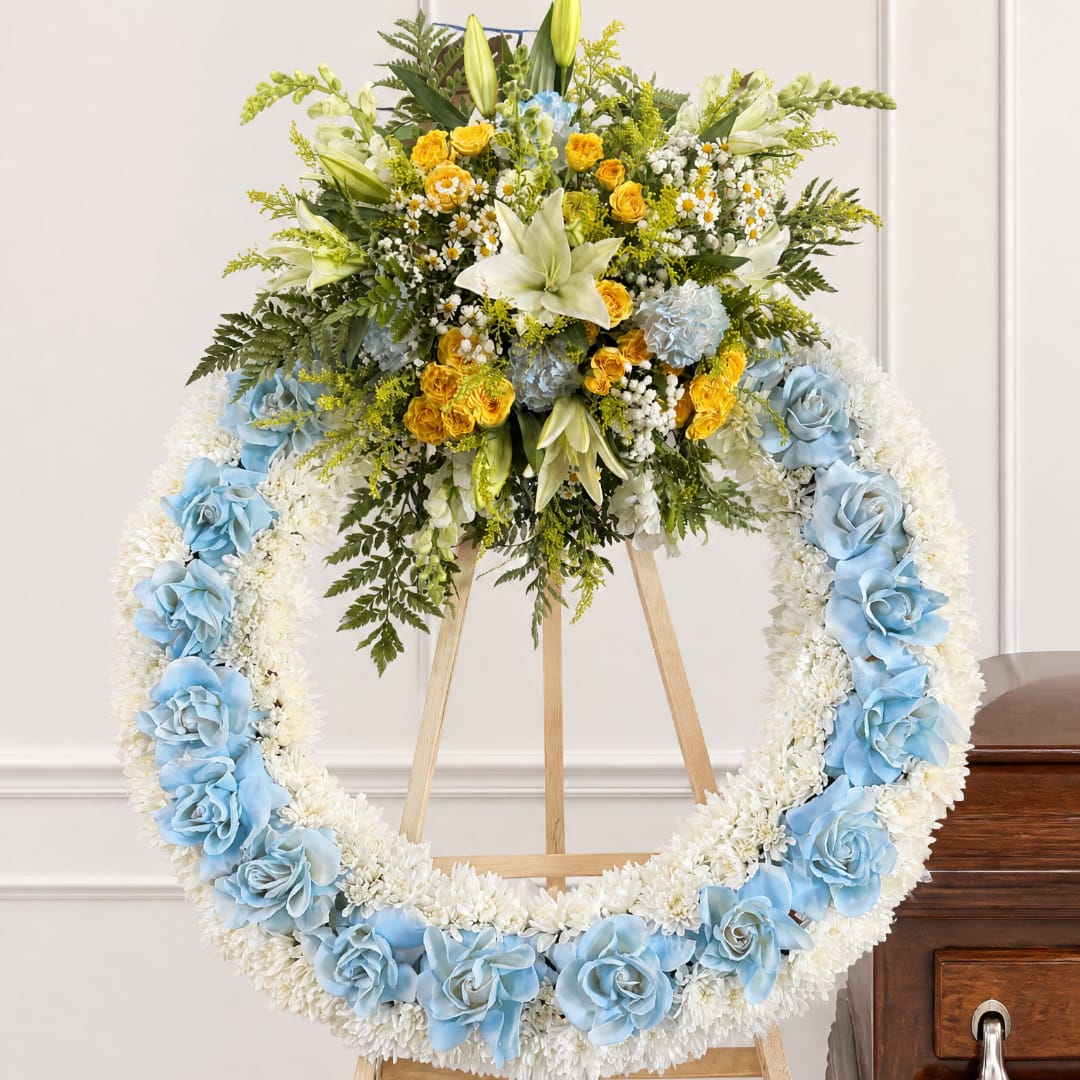 Large floral funeral wreath on an easel with blue and white flowers