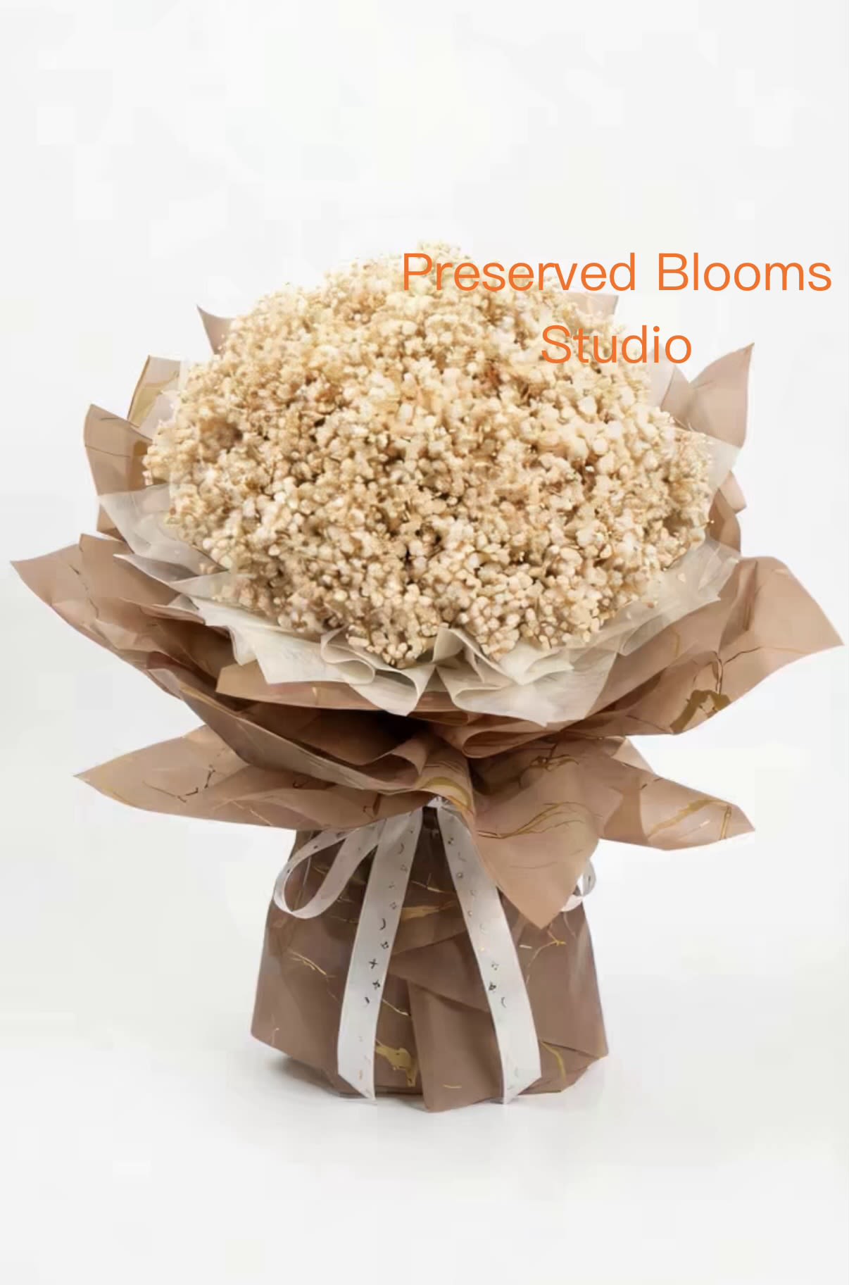 Large bouquet of small cream preserved flowers wrapped in layered brown paper with white ribbon