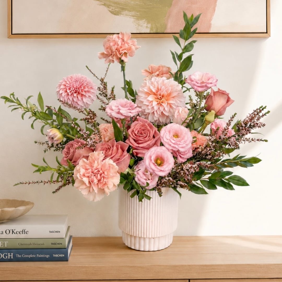 Pink and peach floral arrangement in a ribbed white vase