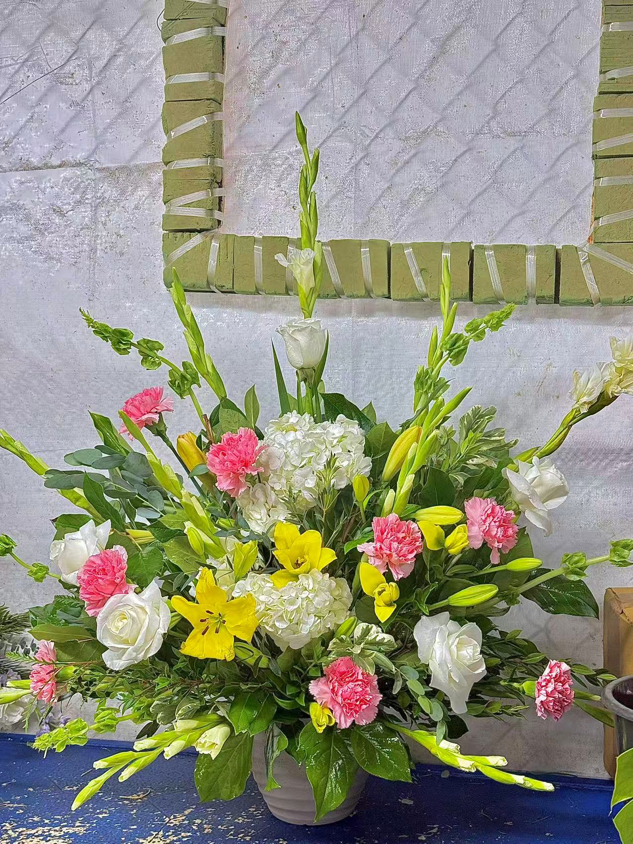 Large mixed floral arrangement in a gray vase with white, pink, and yellow blooms