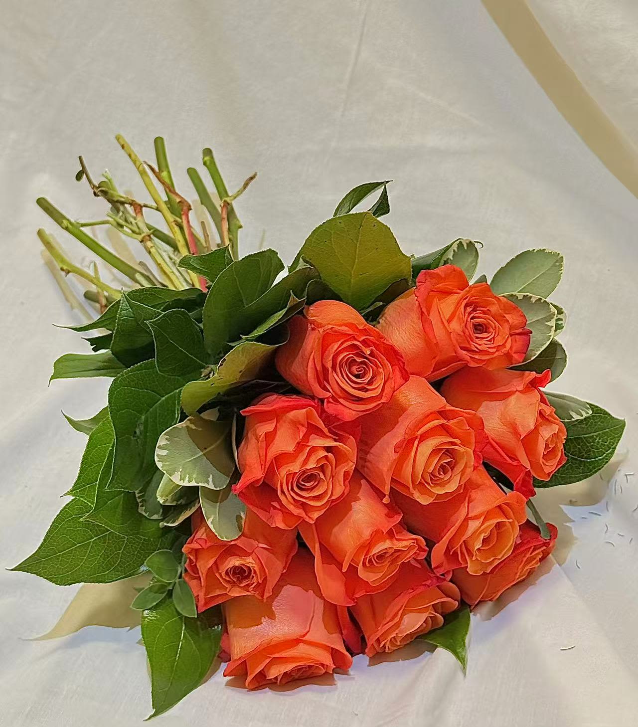 Bouquet of orange roses with green foliage on white wrapping