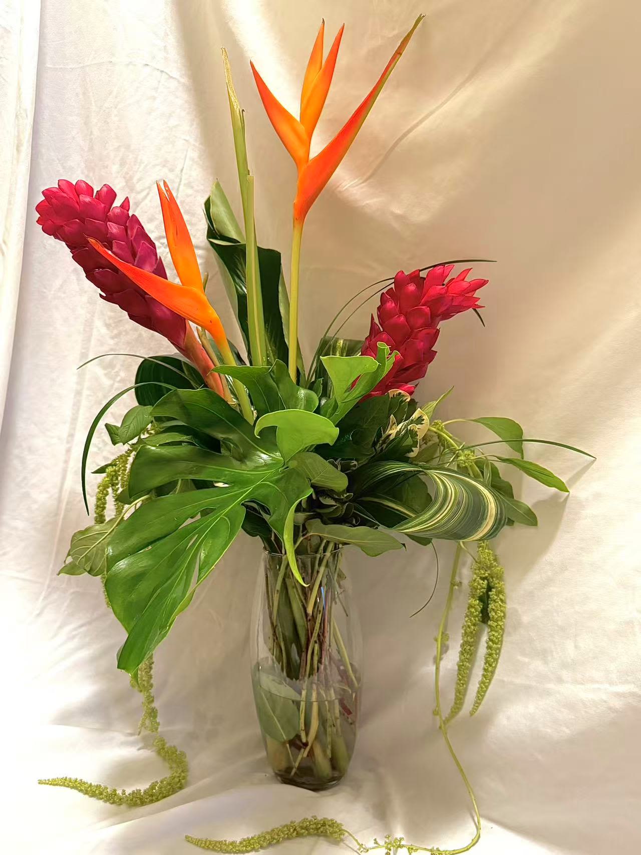 Tropical bouquet with orange bird of paradise and pink ginger in a glass vase