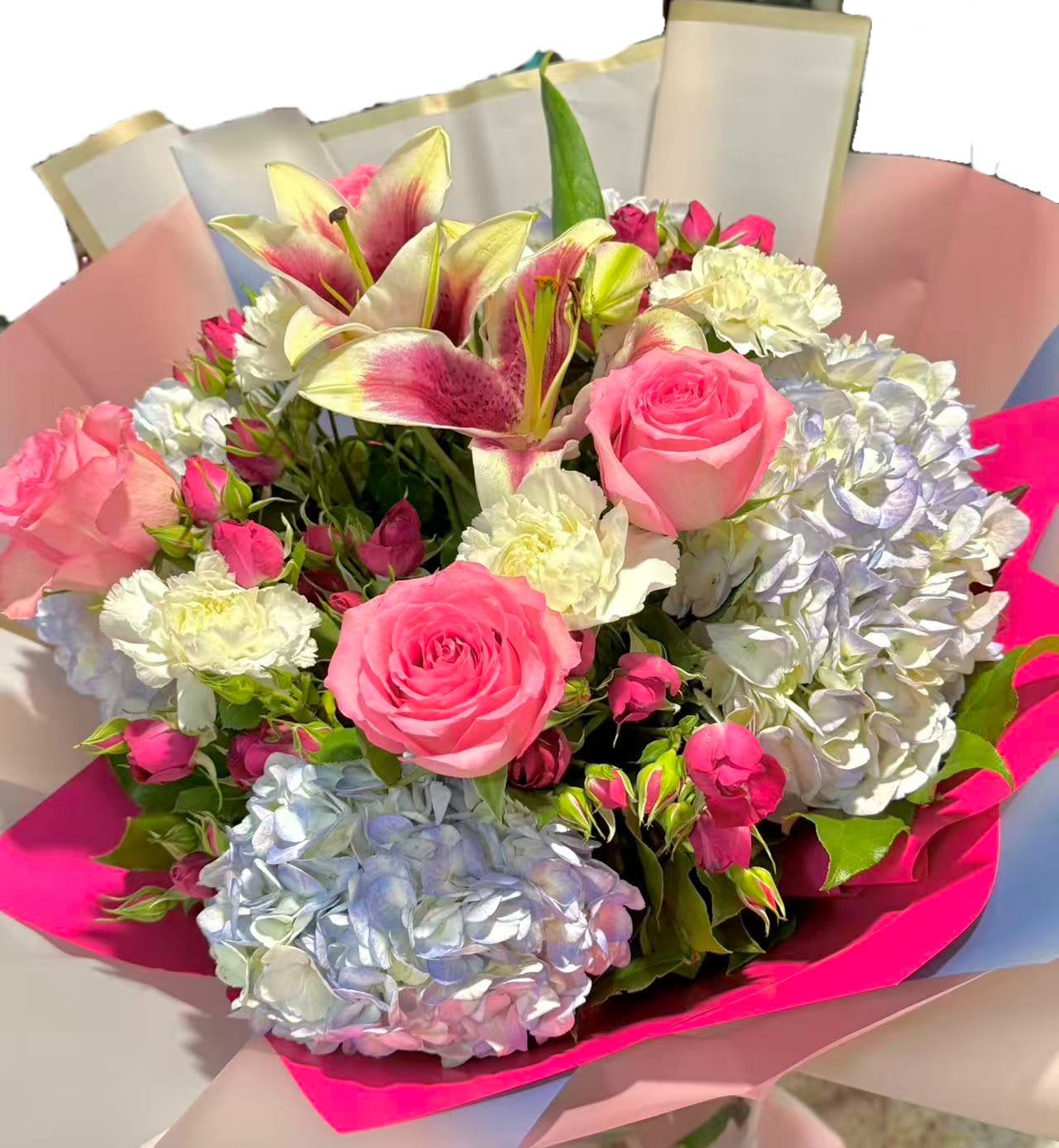 Bouquet of pink roses, lilies, and hydrangeas wrapped in pink paper