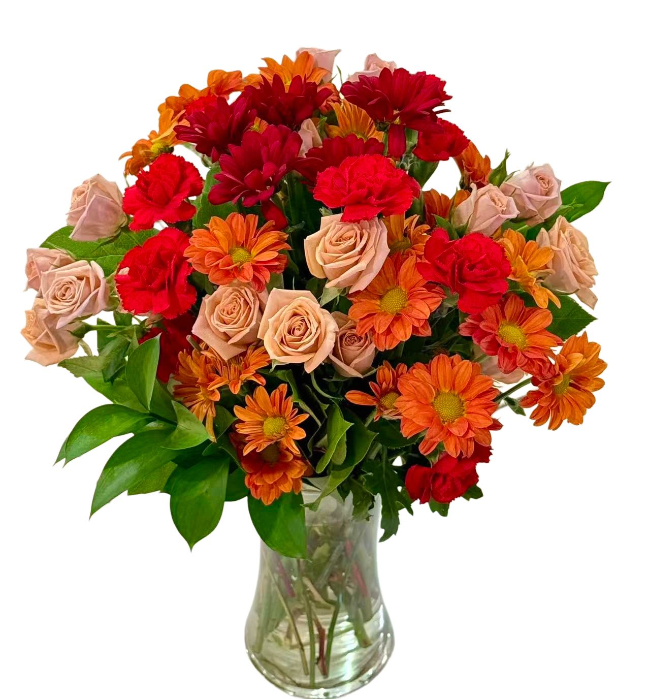 Autumn Glow by Tiffany’s Blooms - A cheerful arrangement featuring warm red roses, soft peach roses, vibrant orange daisies, bold red carnations, and fresh greenery, beautifully designed in a classic clear glass vase.  With rich autumn-inspired tones of red and orange, this arrangement brings warmth, joy, and positive energy—perfect for brightening any space or celebrating happy moments.  Each arrangement is handcrafted with fresh seasonal blooms. Flower varieties may vary slightly while preserving the overall color palette and lively style.