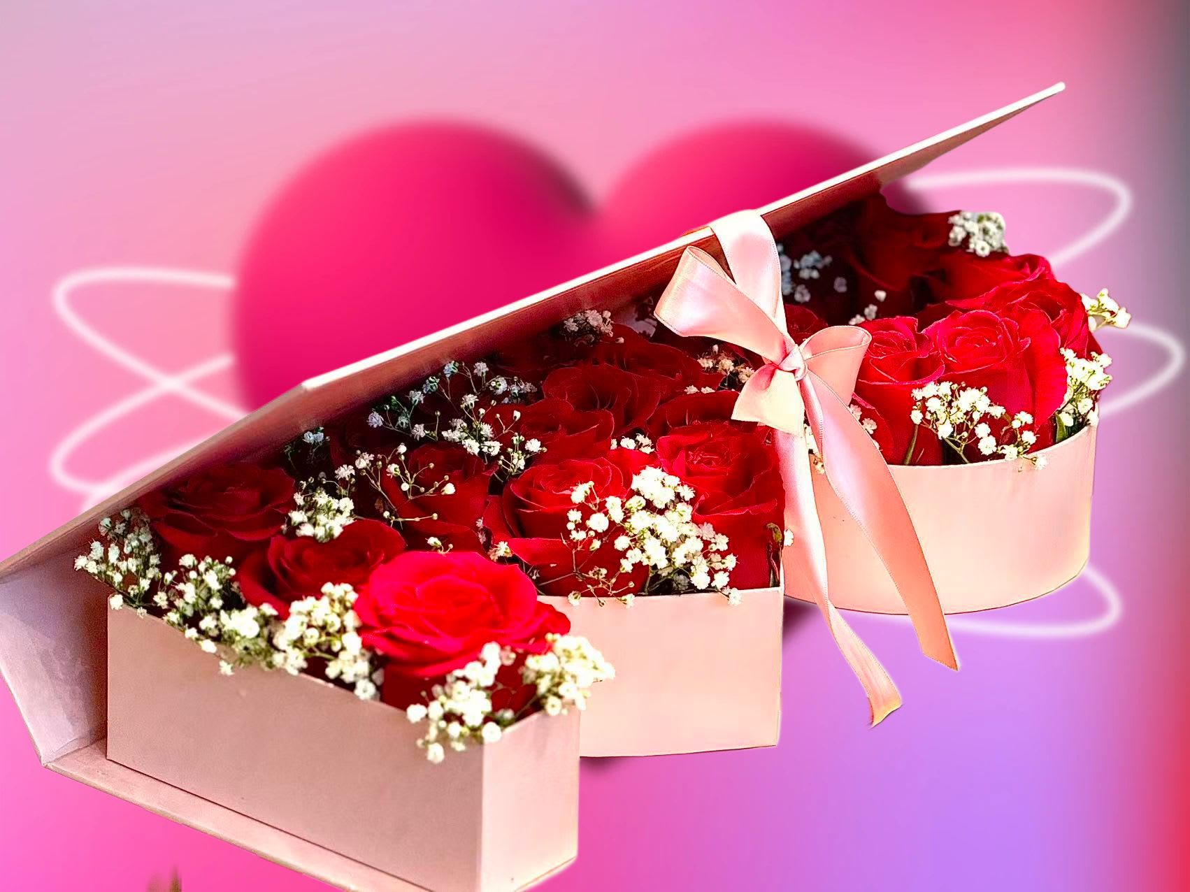 Pink heart-shaped box of red roses with baby's breath and a ribbon