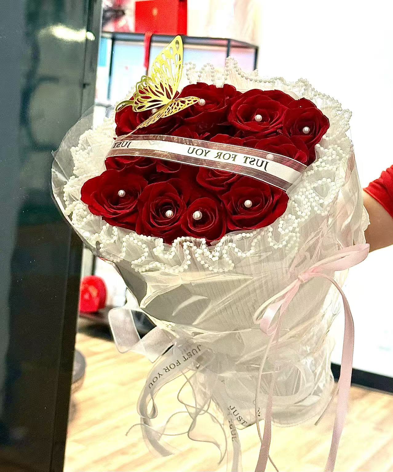 Bouquet of red roses wrapped in white lace and ribbon