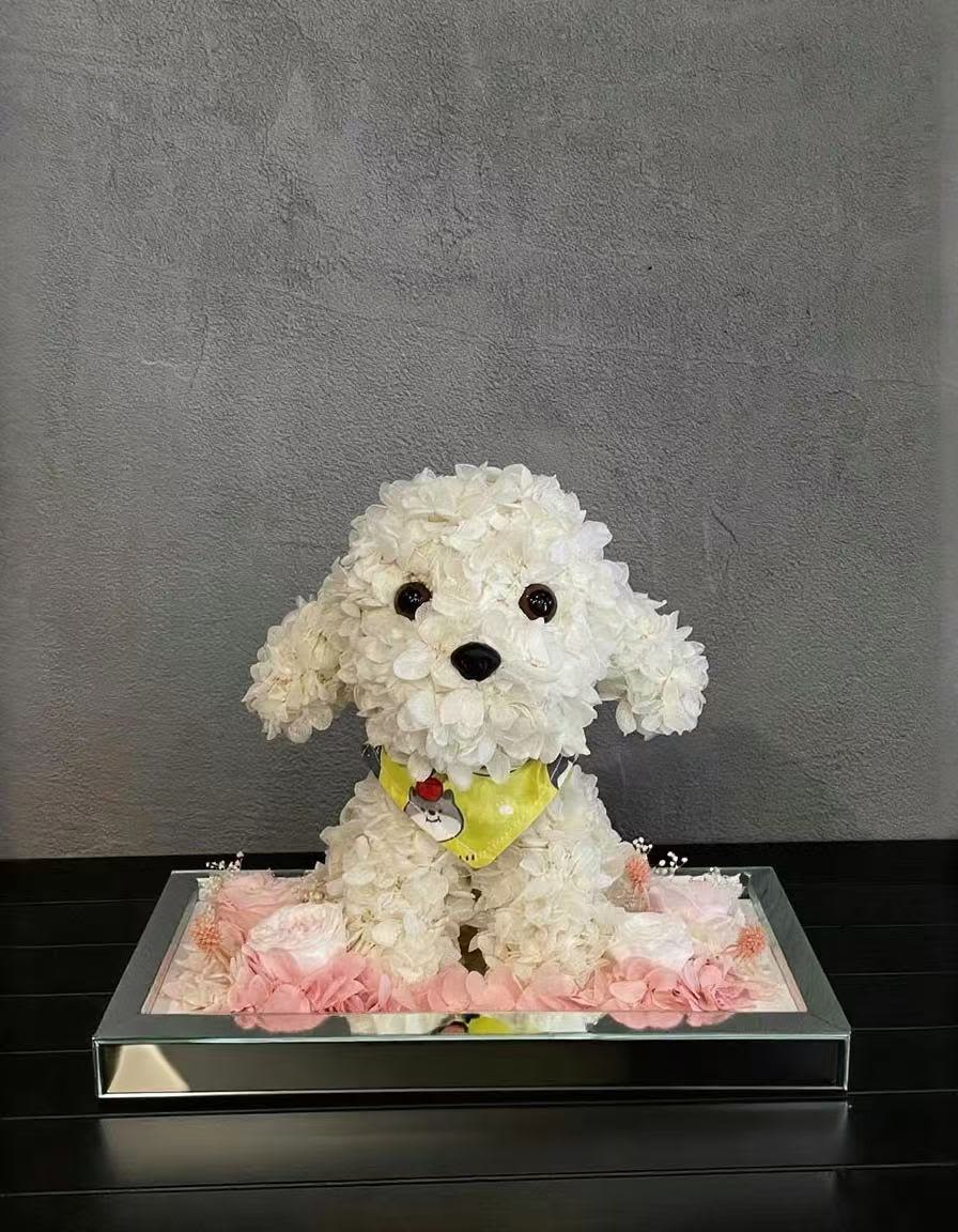 White flower-covered dog figurine in a mirrored tray with pink flowers