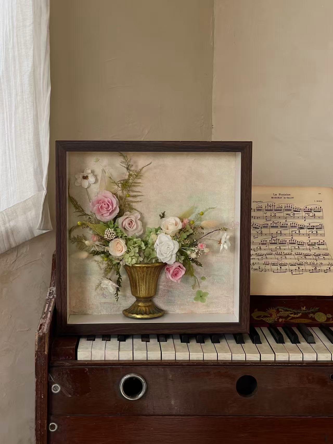 Framed floral arrangement with pink and white roses in a gold vase