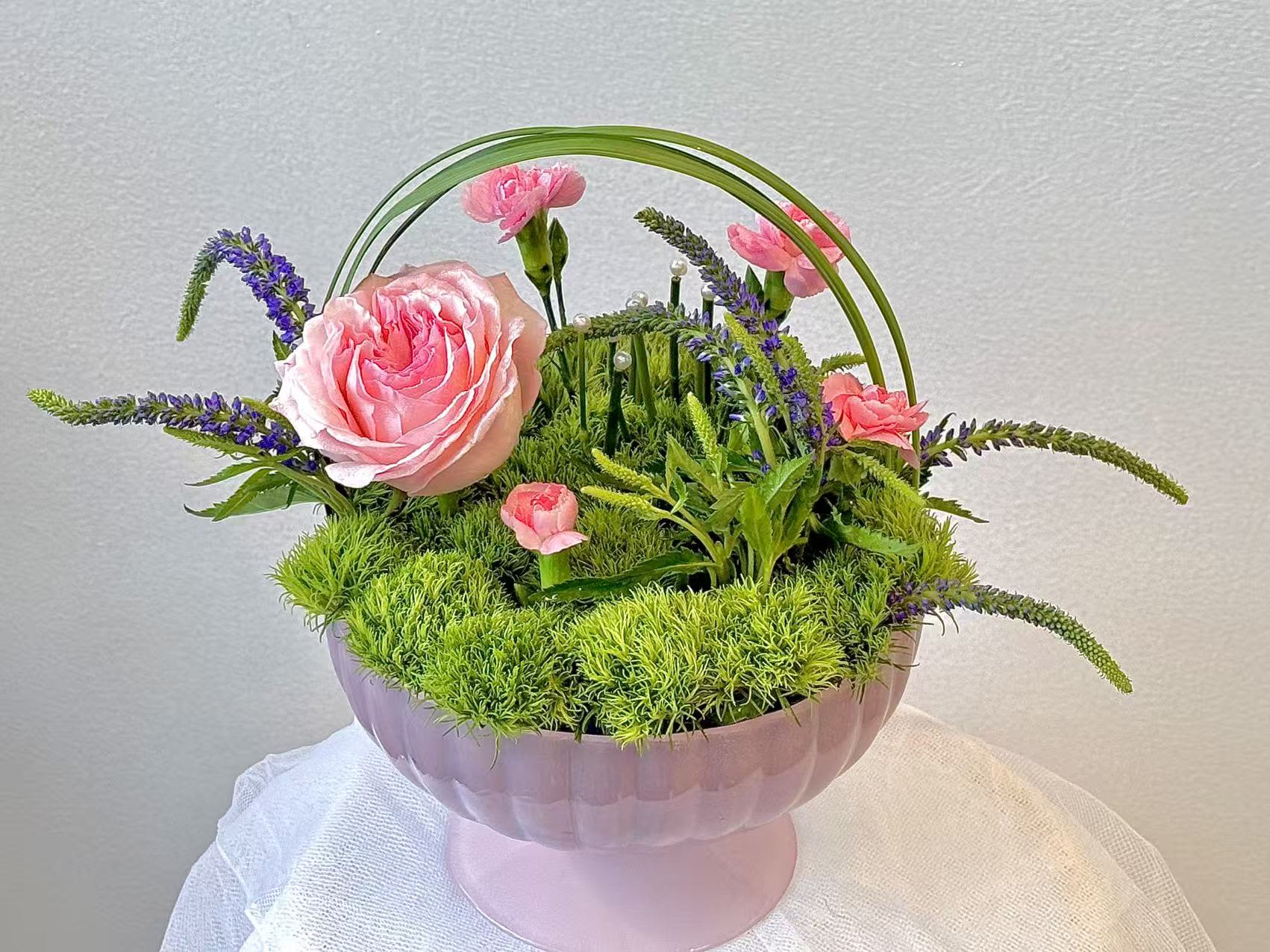 Pink roses and carnations arranged in a pink pedestal bowl